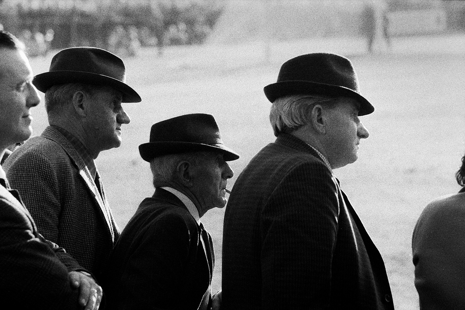 Men watching a football match between Bideford FC and Wadebridge FC, possibly held at Bideford. Three of them are wearing hats. The match was a cup final.