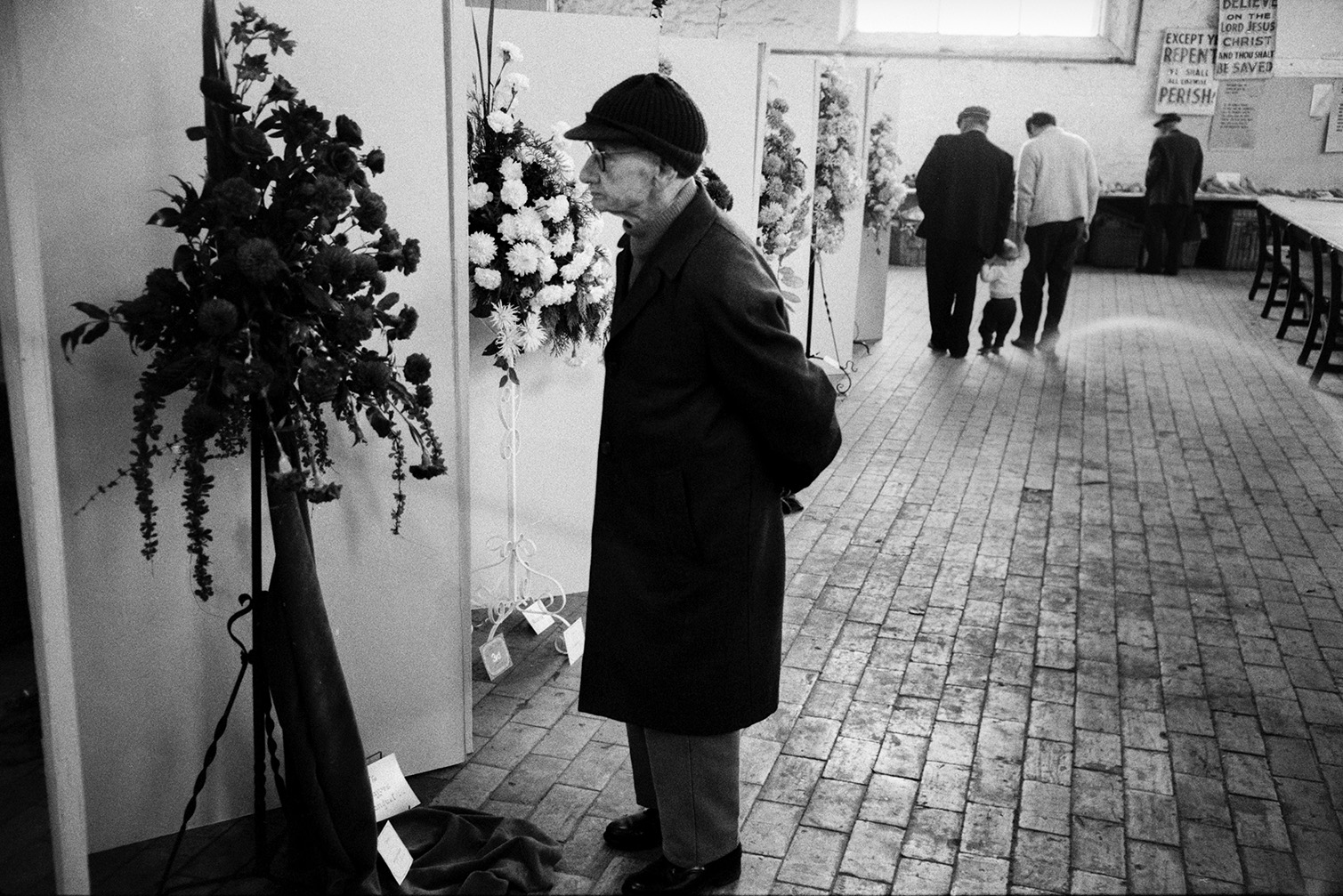 Man looking at a flower display in a pedestal at a flower show in Bideford Pannier Market.