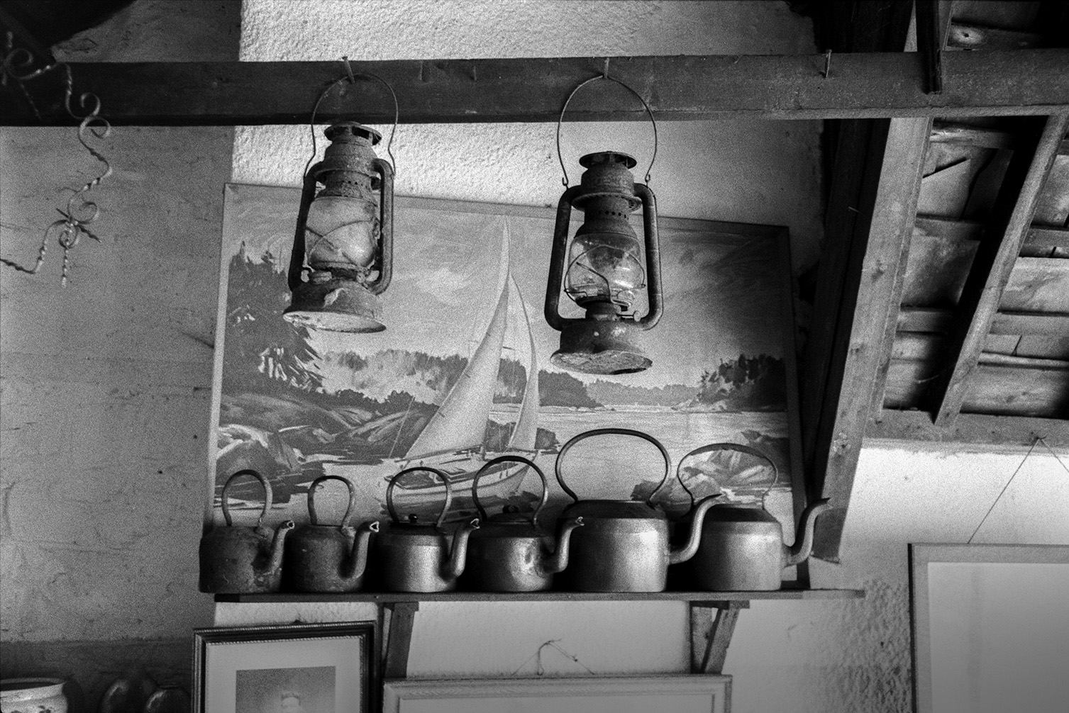 Interior of Mrs Moantes Antique Shop in Chittlehampton. A row of kettles on a shelf, paintings and lamps are visible.