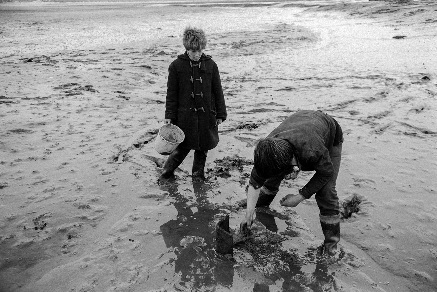 Two boys exploring mud flats on the estuary of the Taw River, possibly near Crow Point, Braunton.