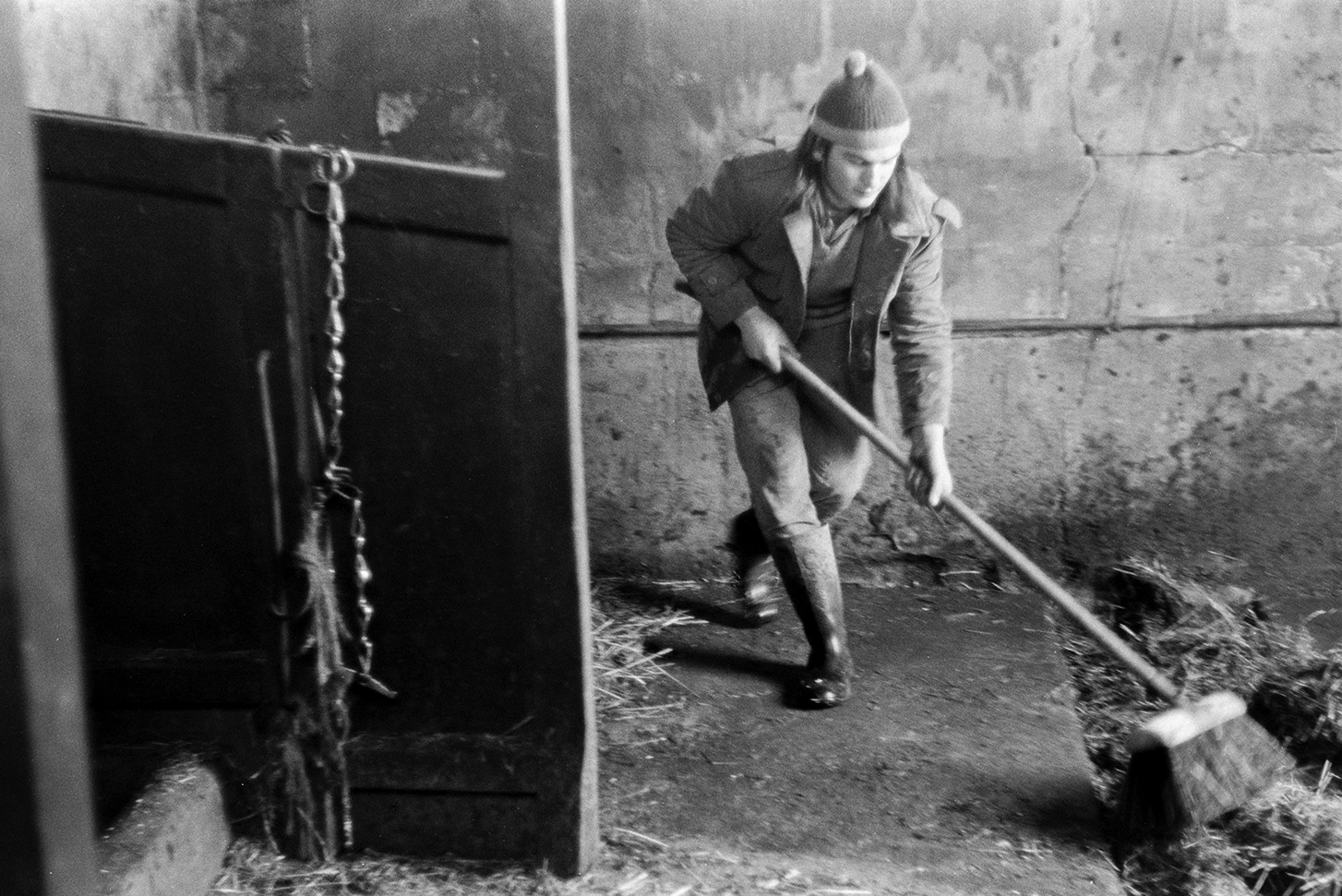 Derek Bright mucking out a cow shed, using a brush, at Mill Road Farm, Beaford. The farm was also known as Jeffrys.