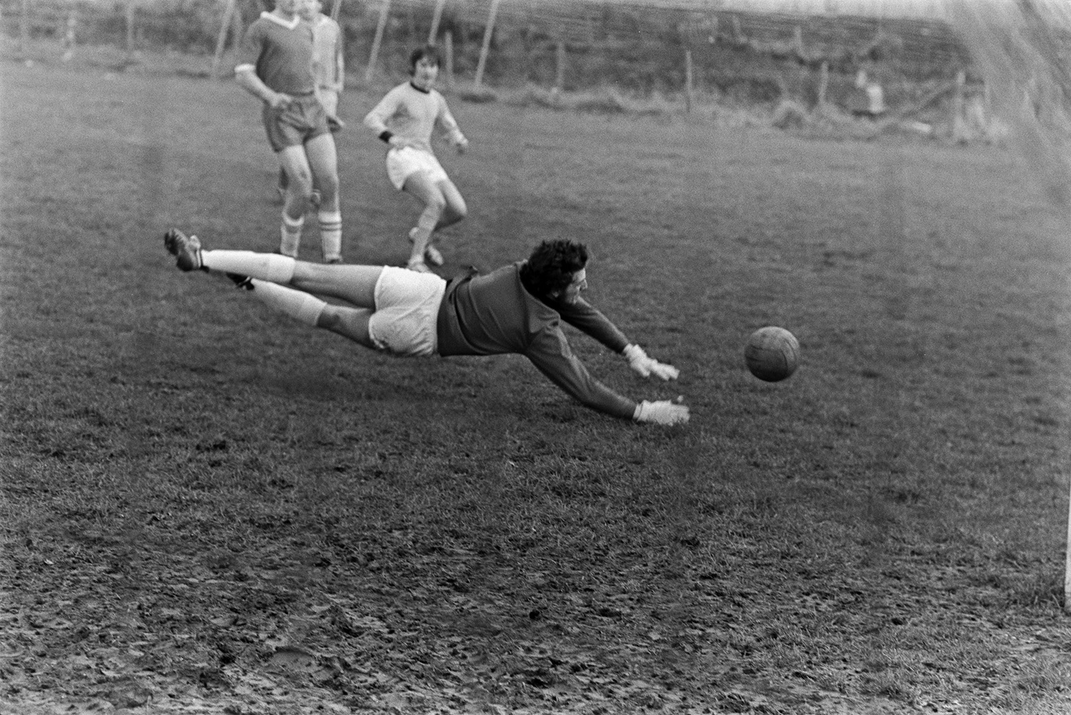 Football match between Merton and Dolton at Merton. The goal keeper is diving for the football and saving a goal.
