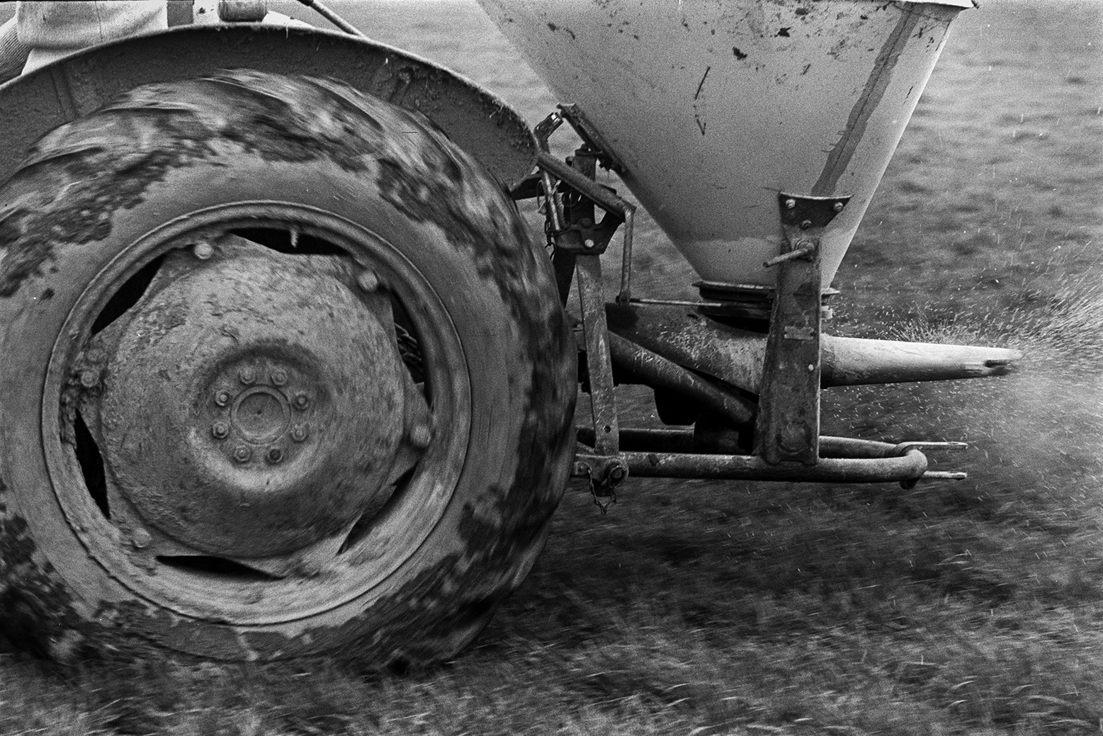 A tractor and fertilizer spreader distributing fertilizer over a field at Mill Road Farm, Beaford. The farm was also known as Jeffrys.