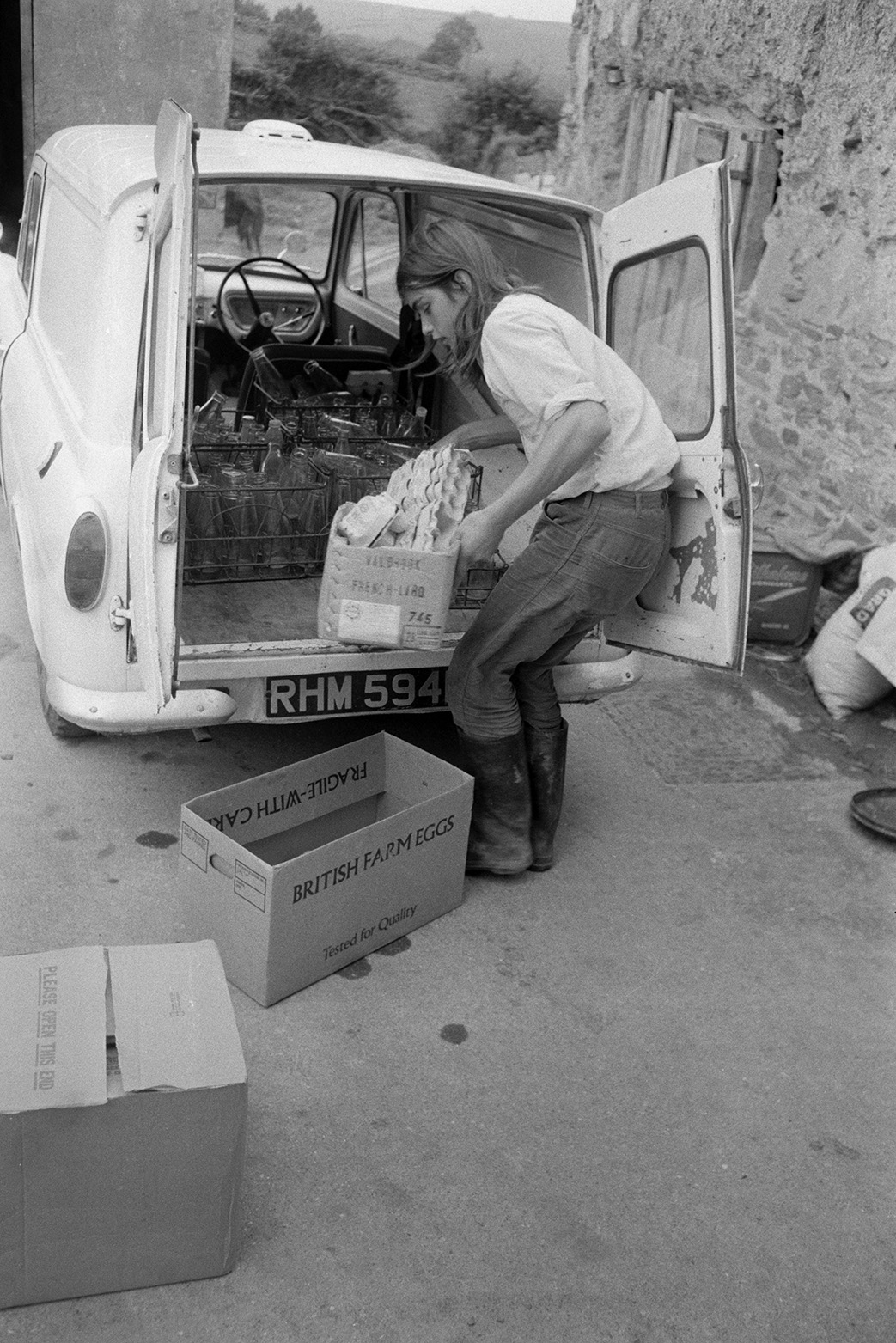 Derek Bright unloading empty milk bottleS and egg boxes from a van in the farmyard at Mill Road Farm, Beaford, after Ivor Bourne's milk round. The farm was also known as Jeffrys.