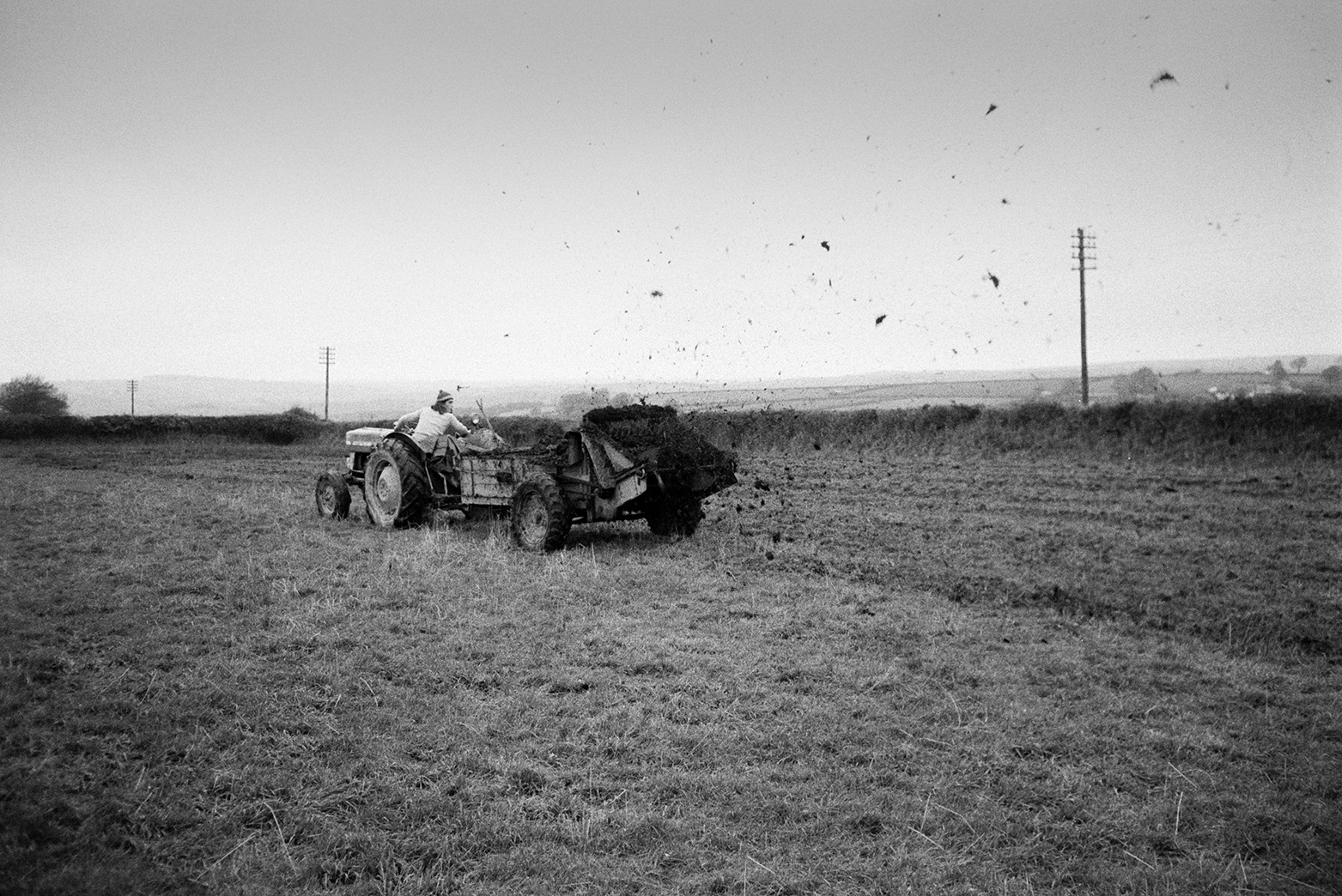 Derek Bright muckspreading in a field at Mill Road Farm, Beaford, using a muck spreader. The farm was also known as Jeffrys.