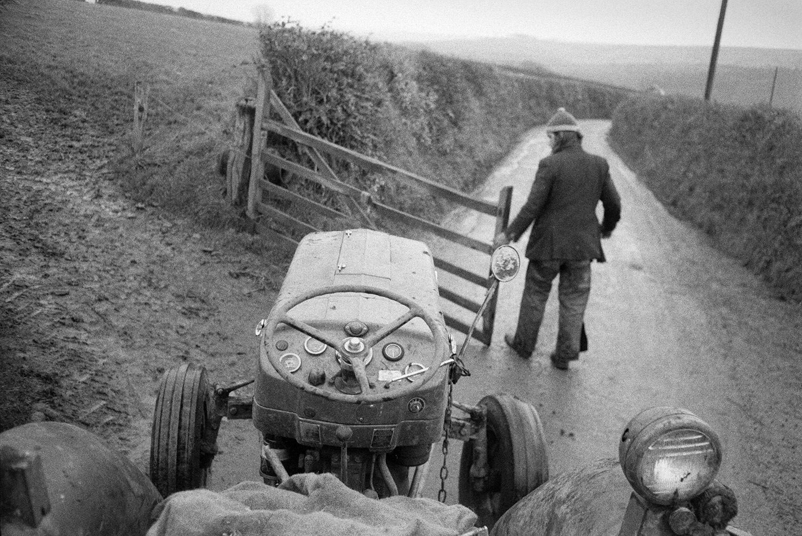 Derek Bright opening a wooden field gate for a tractor to go through, in a lane at Beaford.