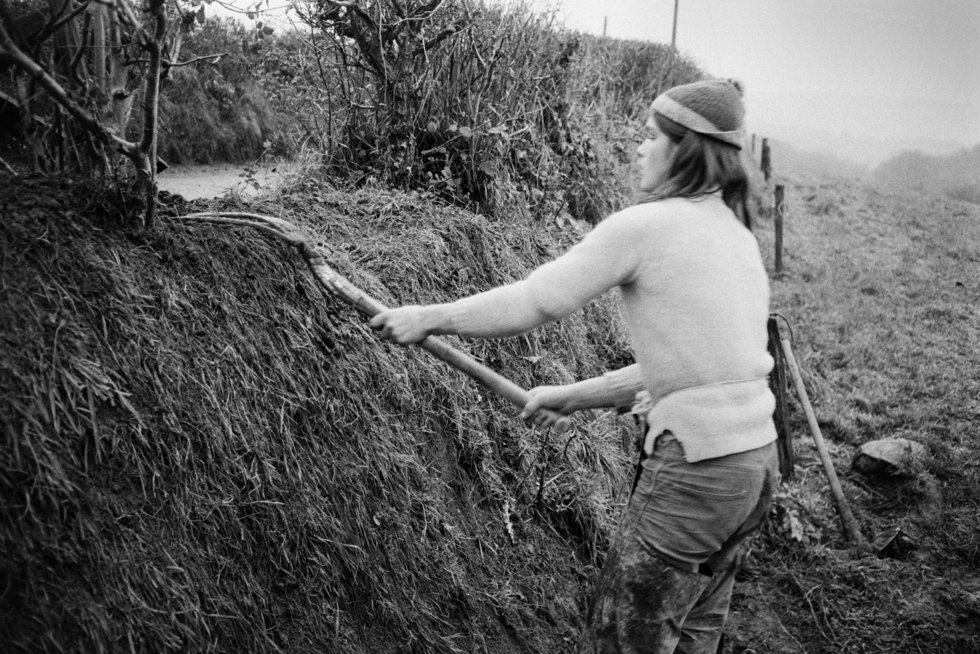 Derek Bright clatting, building up a hedge bank with turf, in a field at Mill Road Farm, Beaford. He is using a fork. The farm was also known as Jeffrys.
