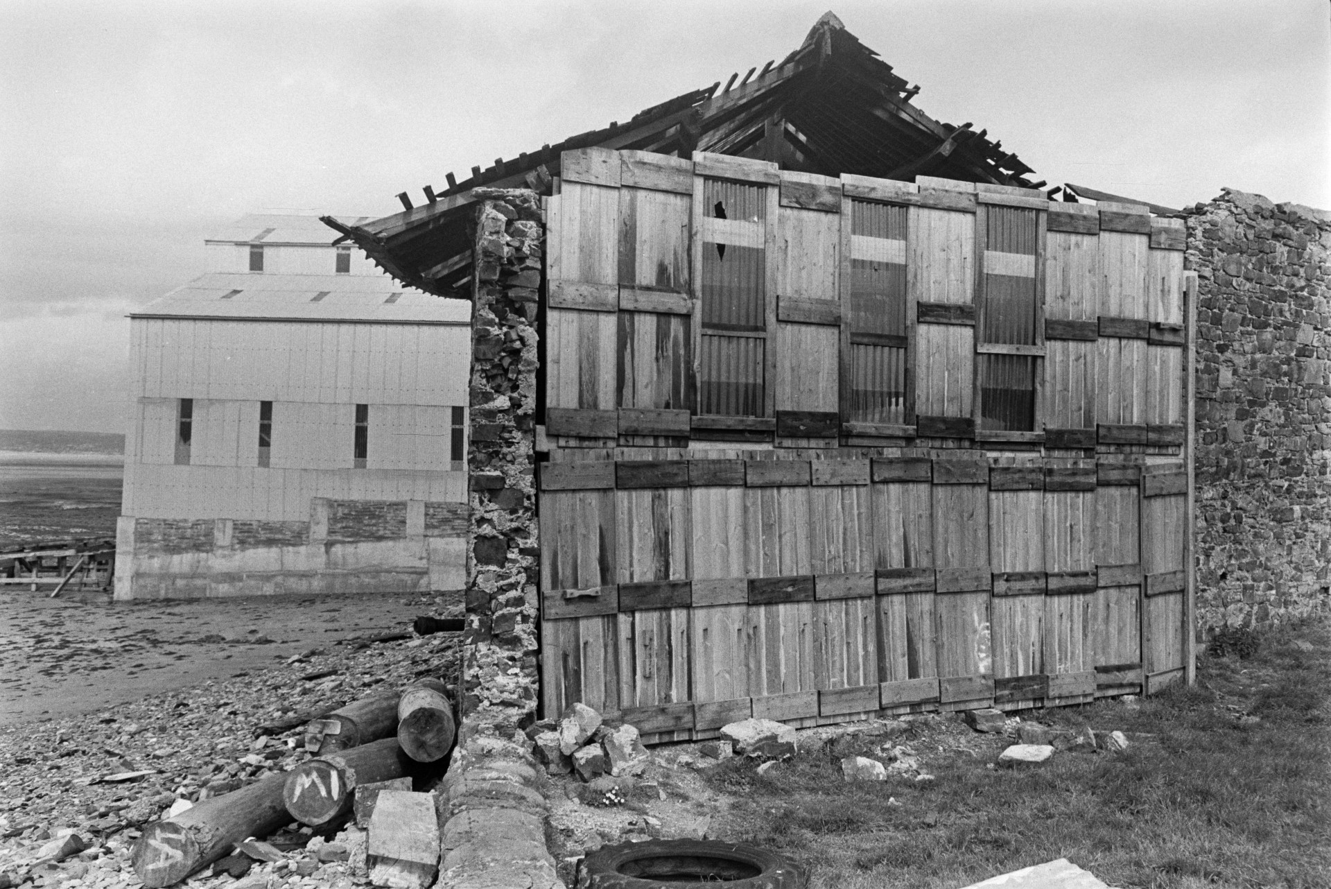 Buildings at Appledore shipyard. A stone and wooden building with a collapsing roof is visible in the foreground.