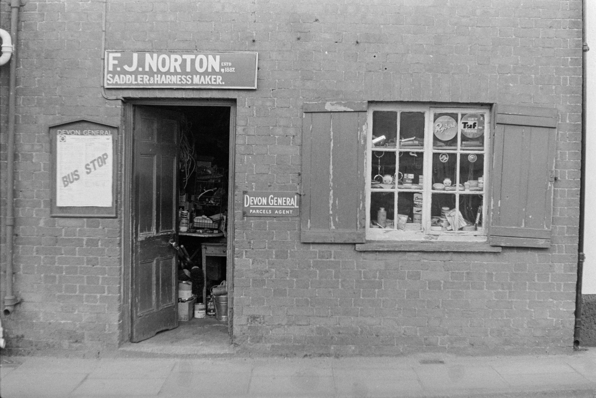 The exterior of F J Norton, Saddler and Harness maker, at Copplestone. The window has shutters.