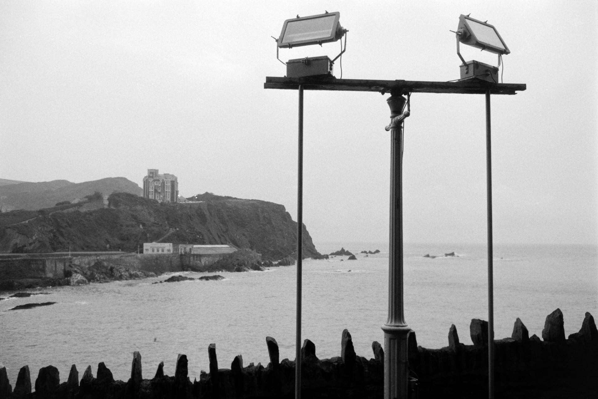 Floodlights on the seafront at Ilfracombe. The sea and a clifftop hotel can be seen in the background.