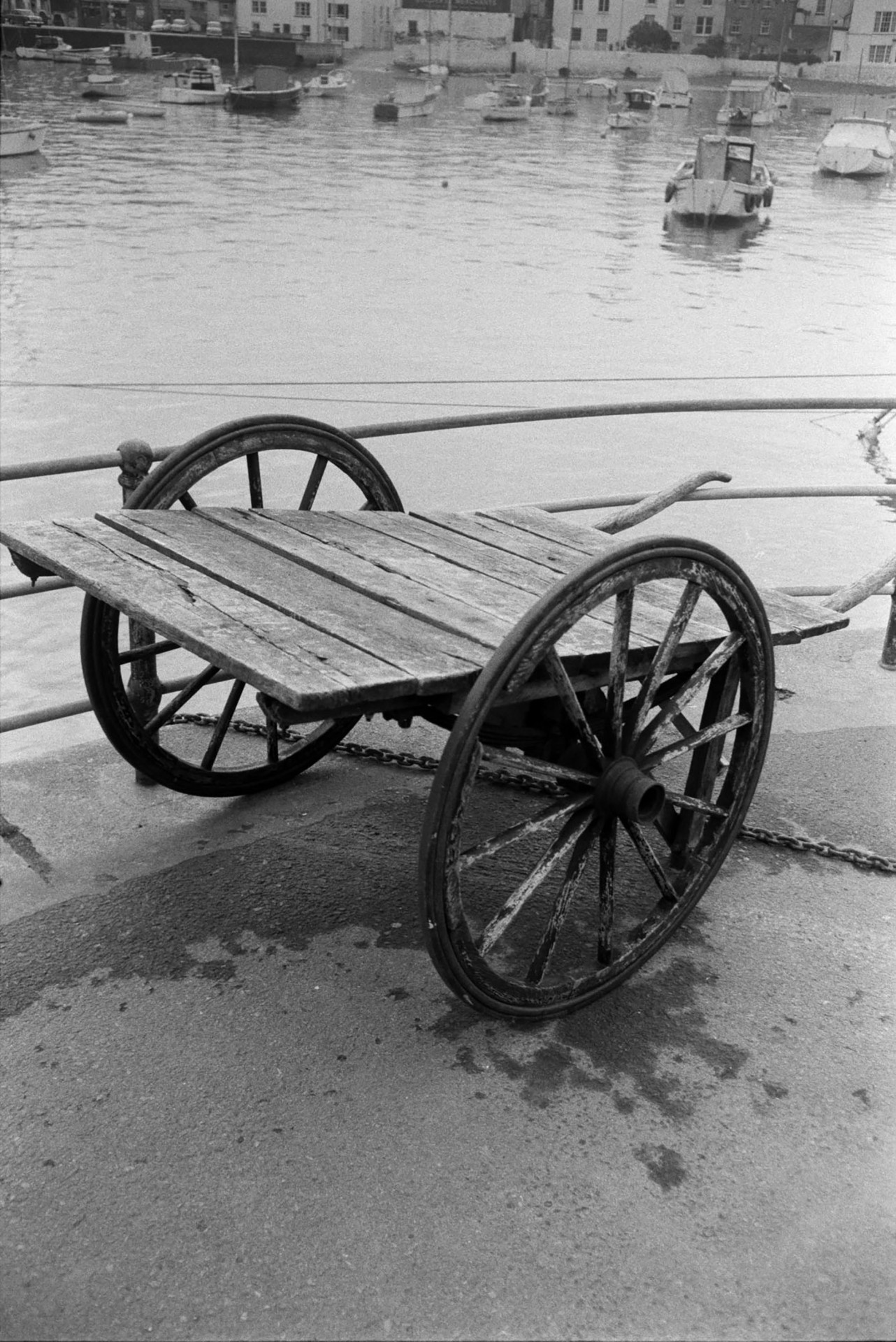 A wooden cart next to the harbour at Ilfracombe. Boats can be seen moored in the harbour.