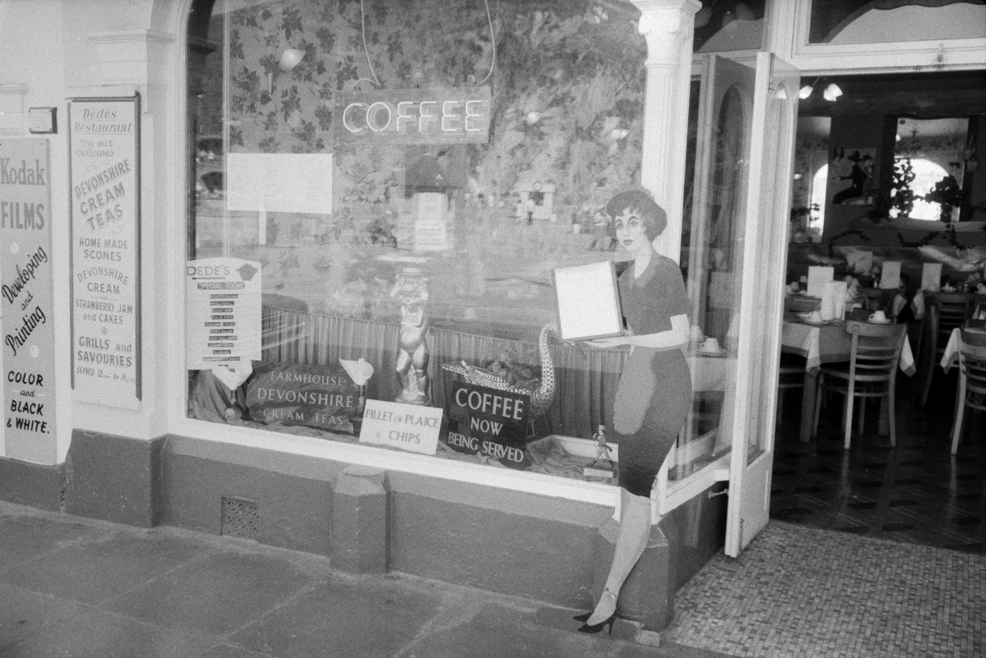 A café window and entrance at Ilfracombe. Adverts for coffee, fish and chips and cream teas are in the window.