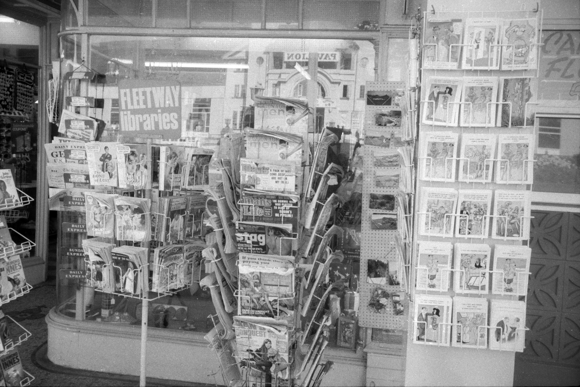 Postcards, newspapers and magazine on display in stands outside a shop in Ilfracombe.