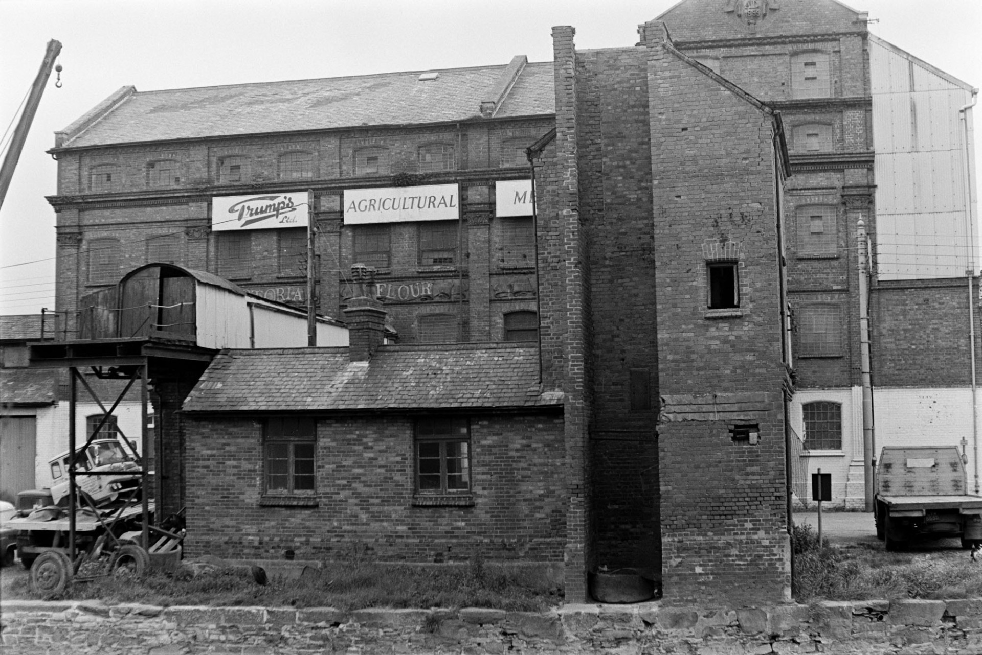 The premises of 'Trumps Agriculture Merchants' near the River Taw at Barnstaple. The building is a brick warehouse or mill.