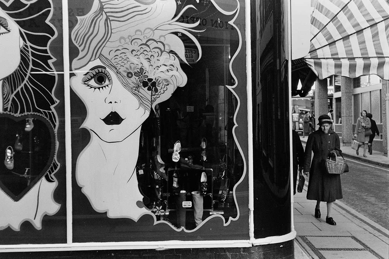 Artwork on a 'Daisy Roots' shoe shop window in Barnstaple. Women are walking along the street nearby.