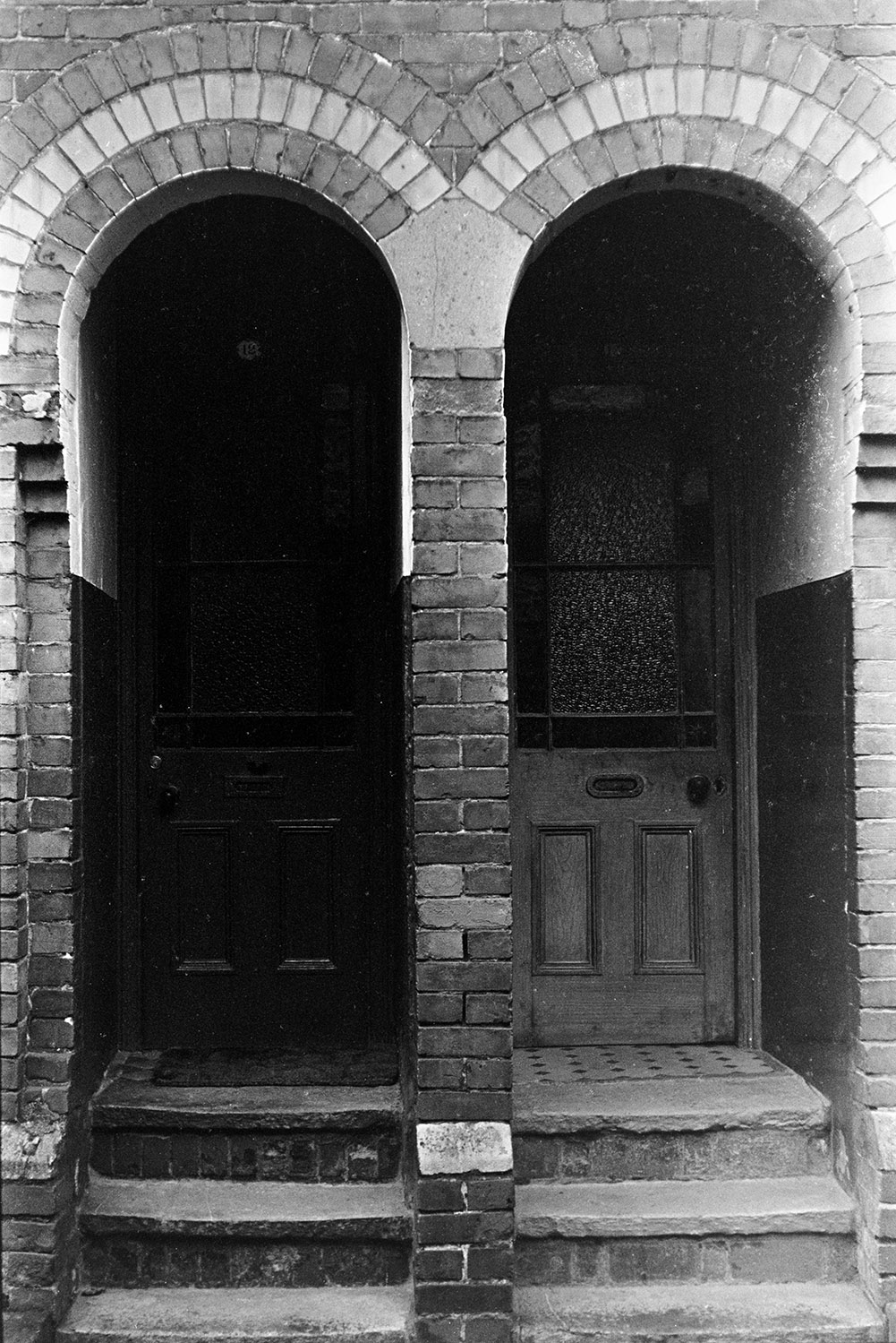 Two arched porches and front door of brick houses in a street in Barnstaple.