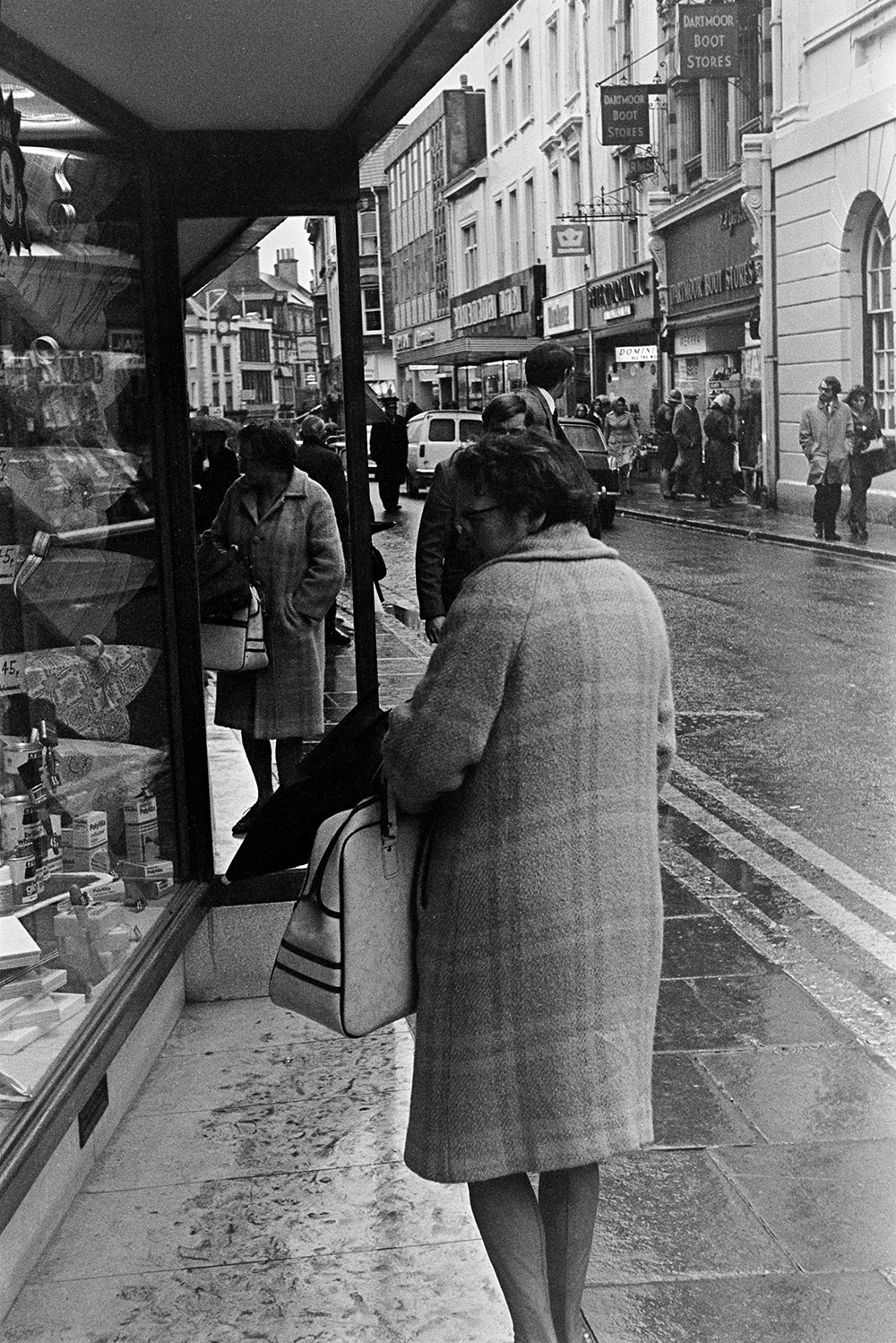 People shopping in Barnstaple High Street. A woman is looking in a shop front window with a mirror in the foreground.