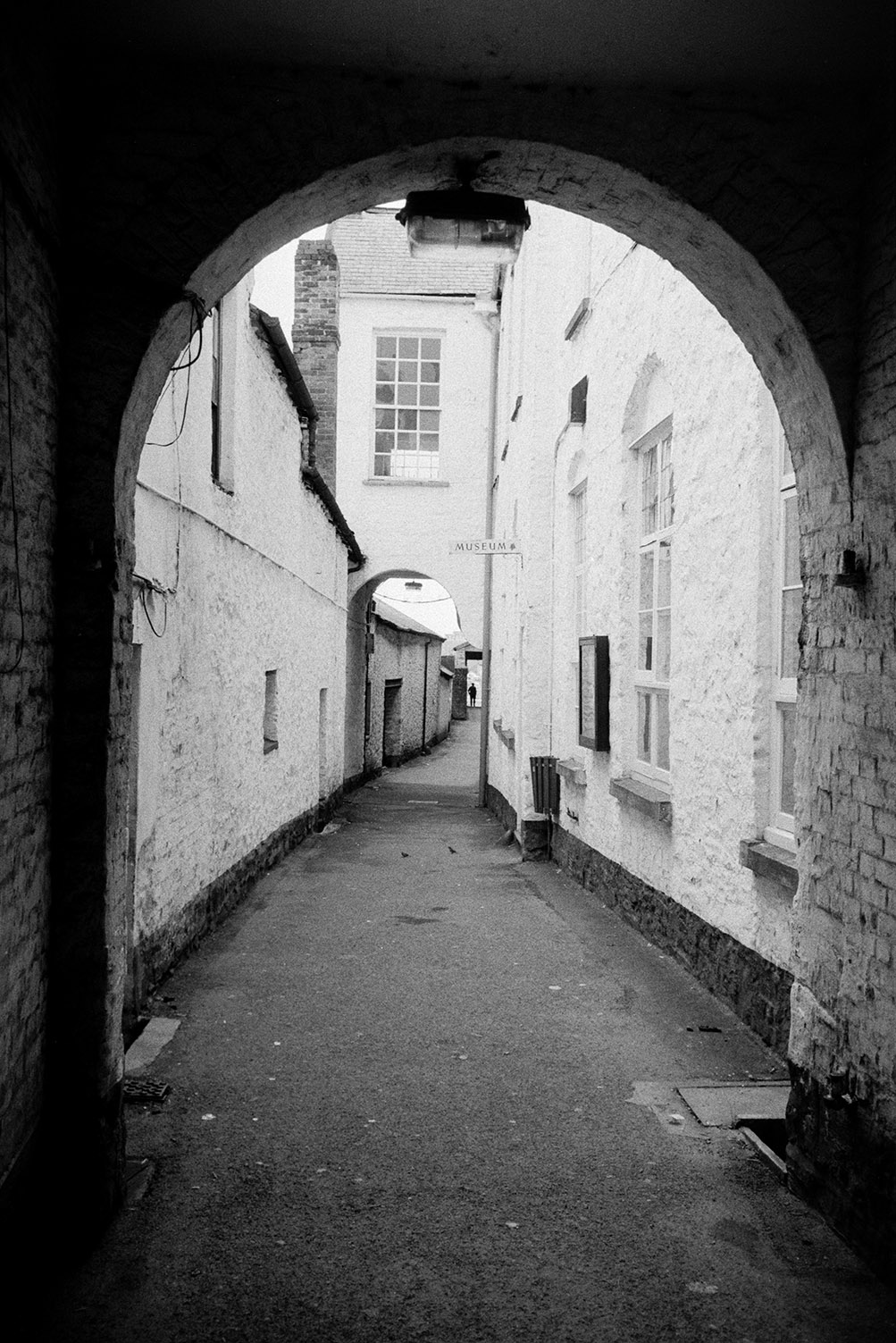 An archway leading down a narrow street in South Molton. A sign for the Museum is on the building.