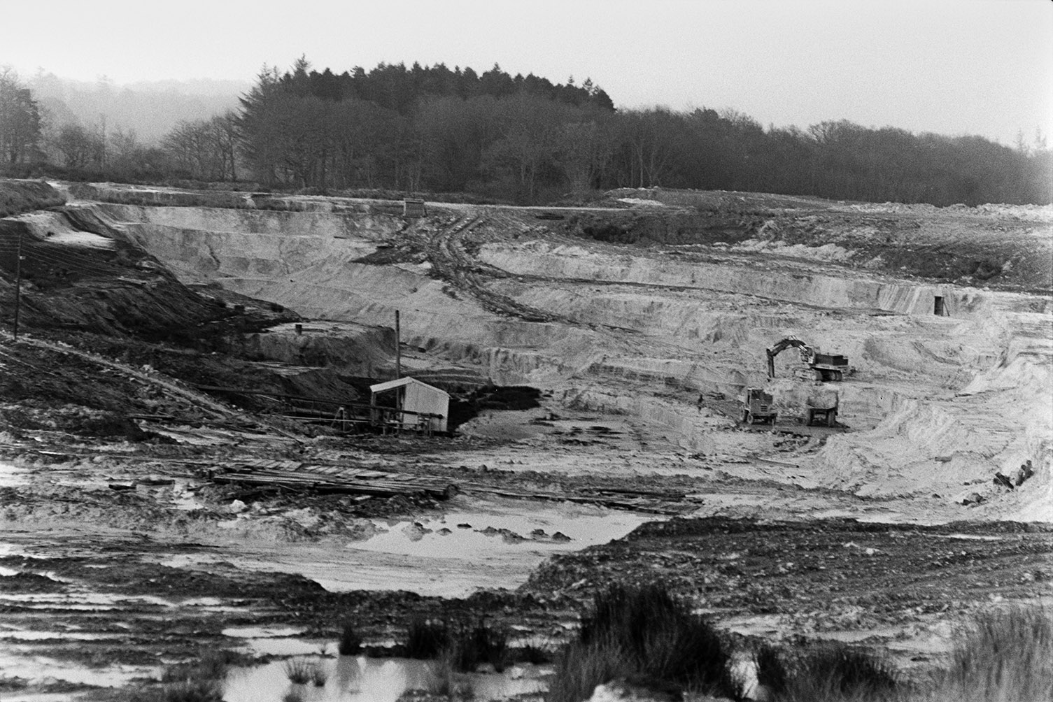 Clay works with a corrugated iron hut at North Devon Clay Pit, Meeth. A digger is excavating in the background.