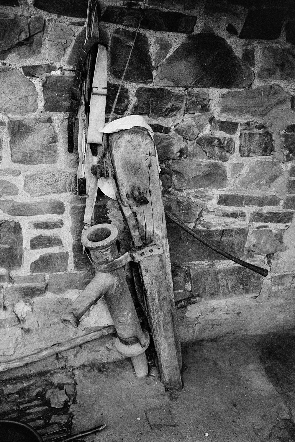 A hand pump by a stone wall at Kingscott.