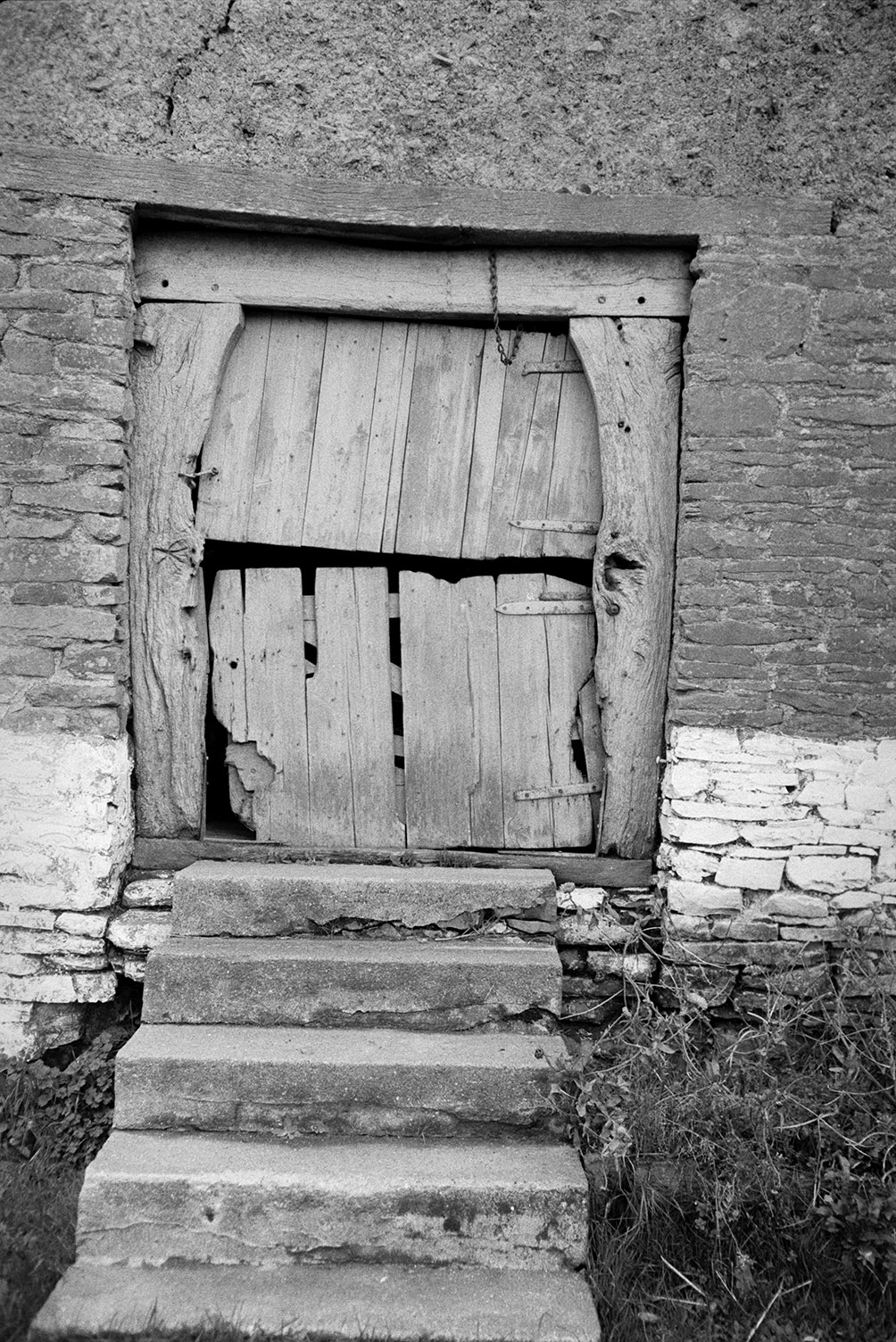 Steps leading up to a wooden stable door in a stone and cob building at Atherington.