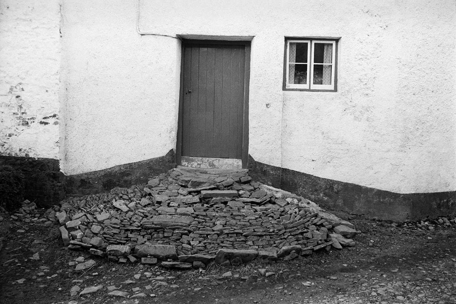A doorway to a house in Atherington with a cobble and stone pathway outside.