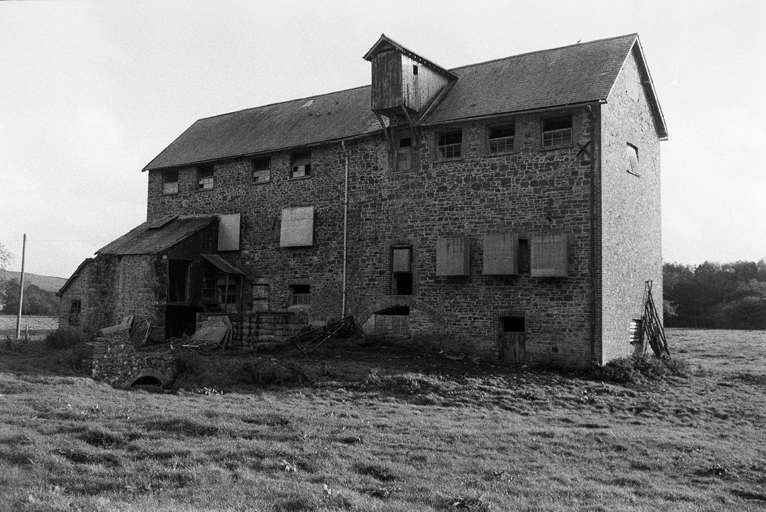 A stone mill building at Weare Giffard, with tress in the background.