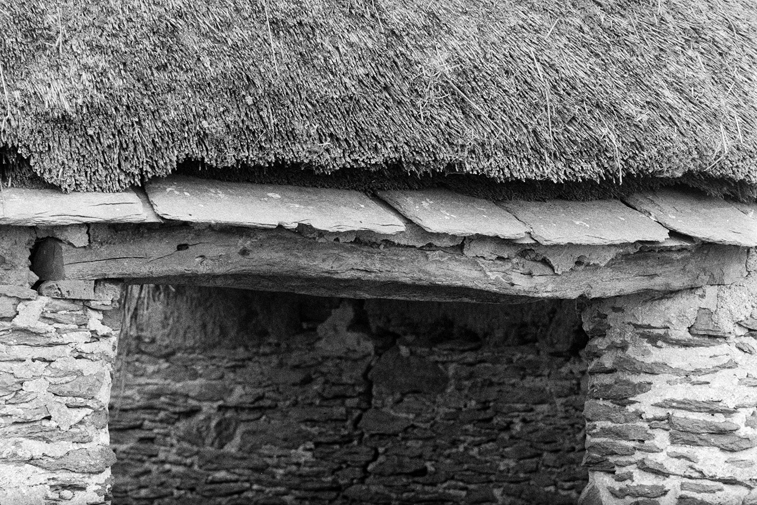 A doorway to a thatched barn with a slate overhang above the wooden lintel, at Braunton Burrows.