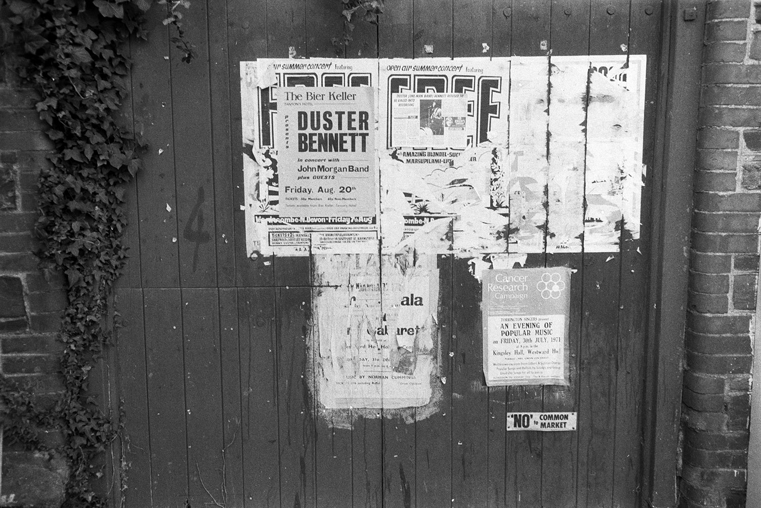 Posters stuck to a wooden doorway in Northam. One poster is advertising Duster Bennett in concert with John Morgan Band at The Bier Keller.
