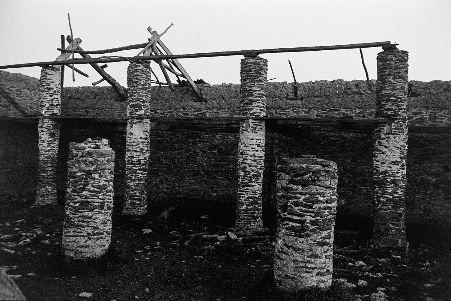 A ruined barn with collapsing stone pillars and exposed wooden roof timbers, on Braunton Burrows.