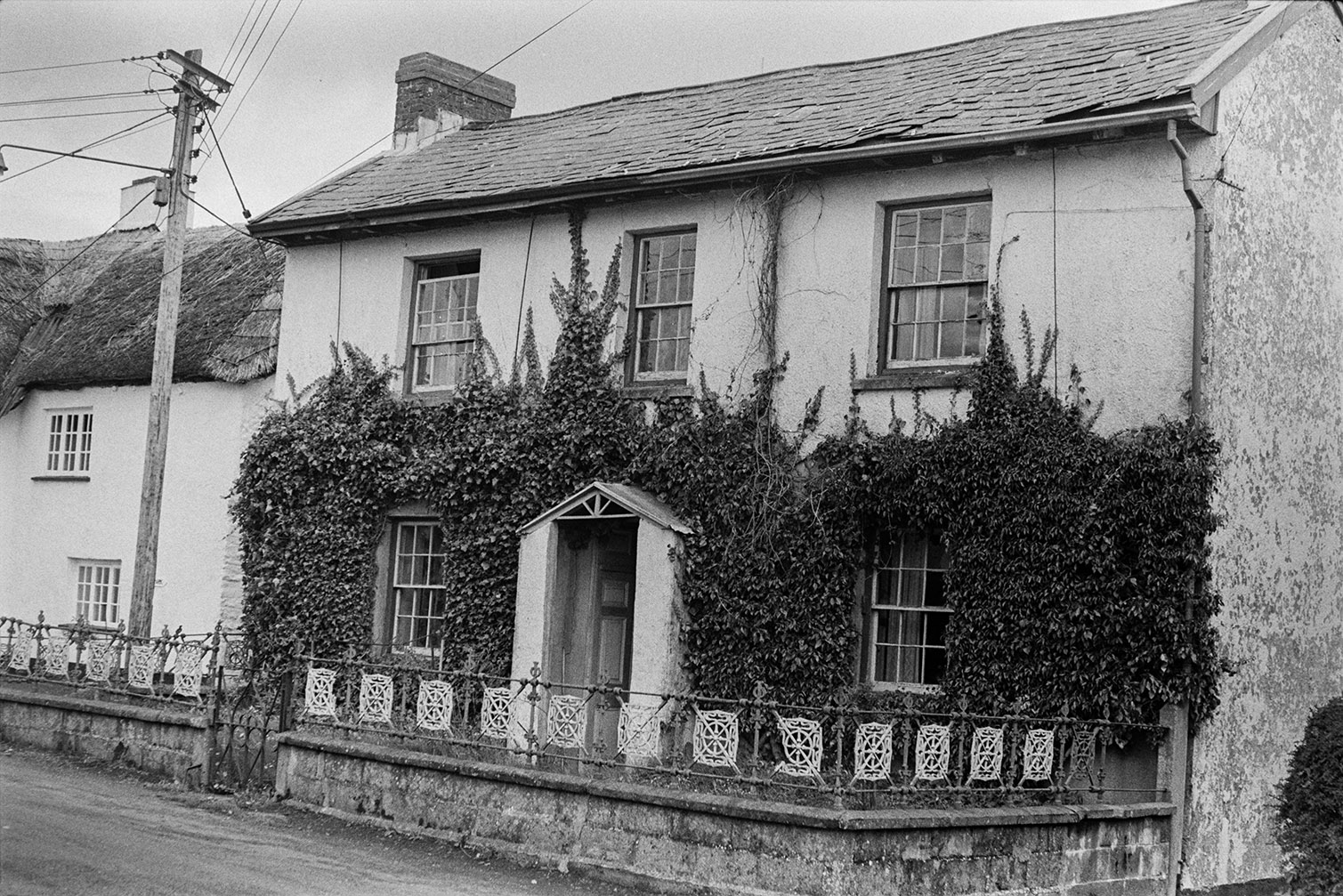 An ivy covered house, possibly at Rackenford, with decorative railings outside.
