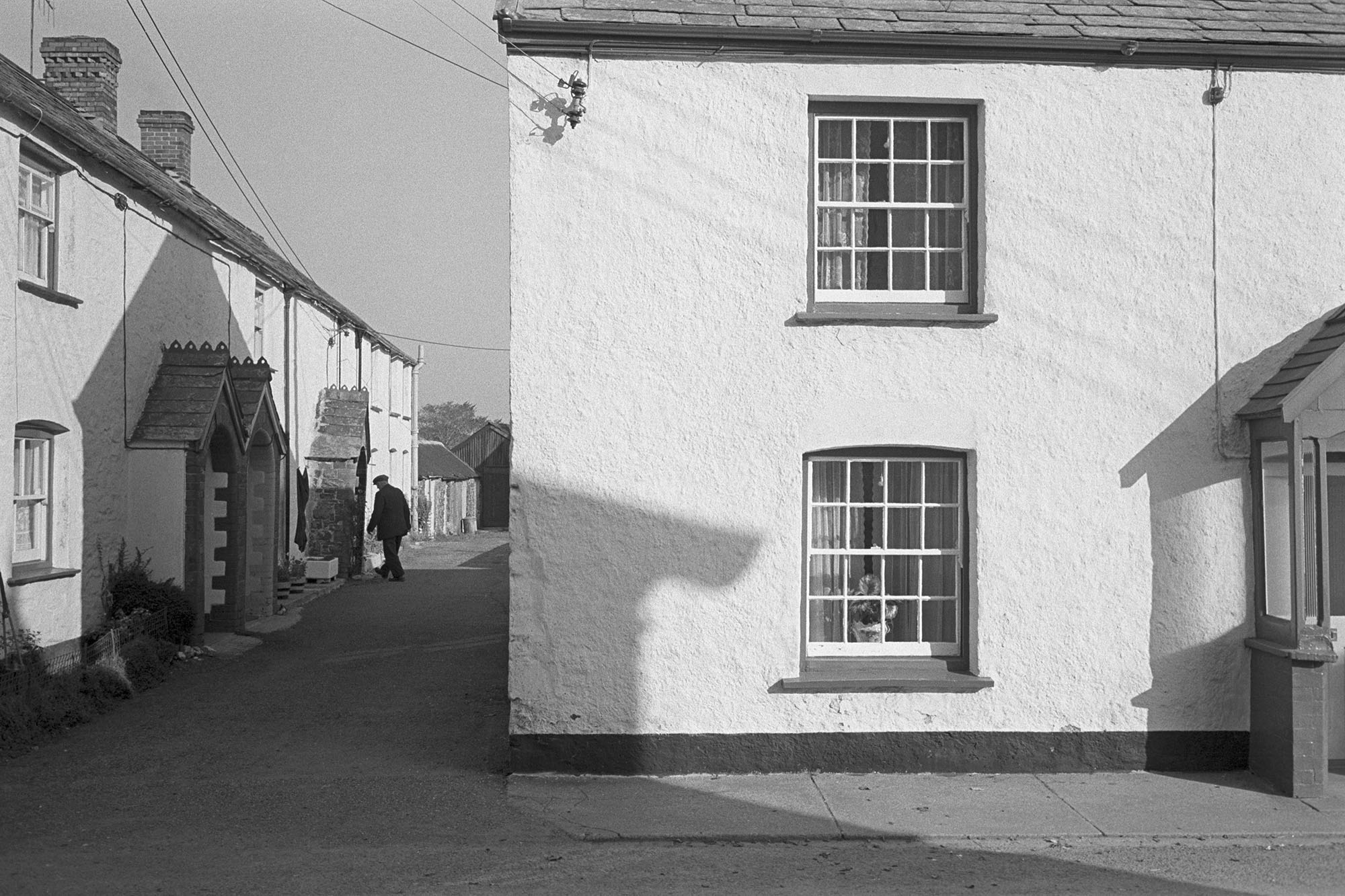 House and row of cottages.<br /> [A man walking down a street at Bradworthy with a row of cottages with porches.]
