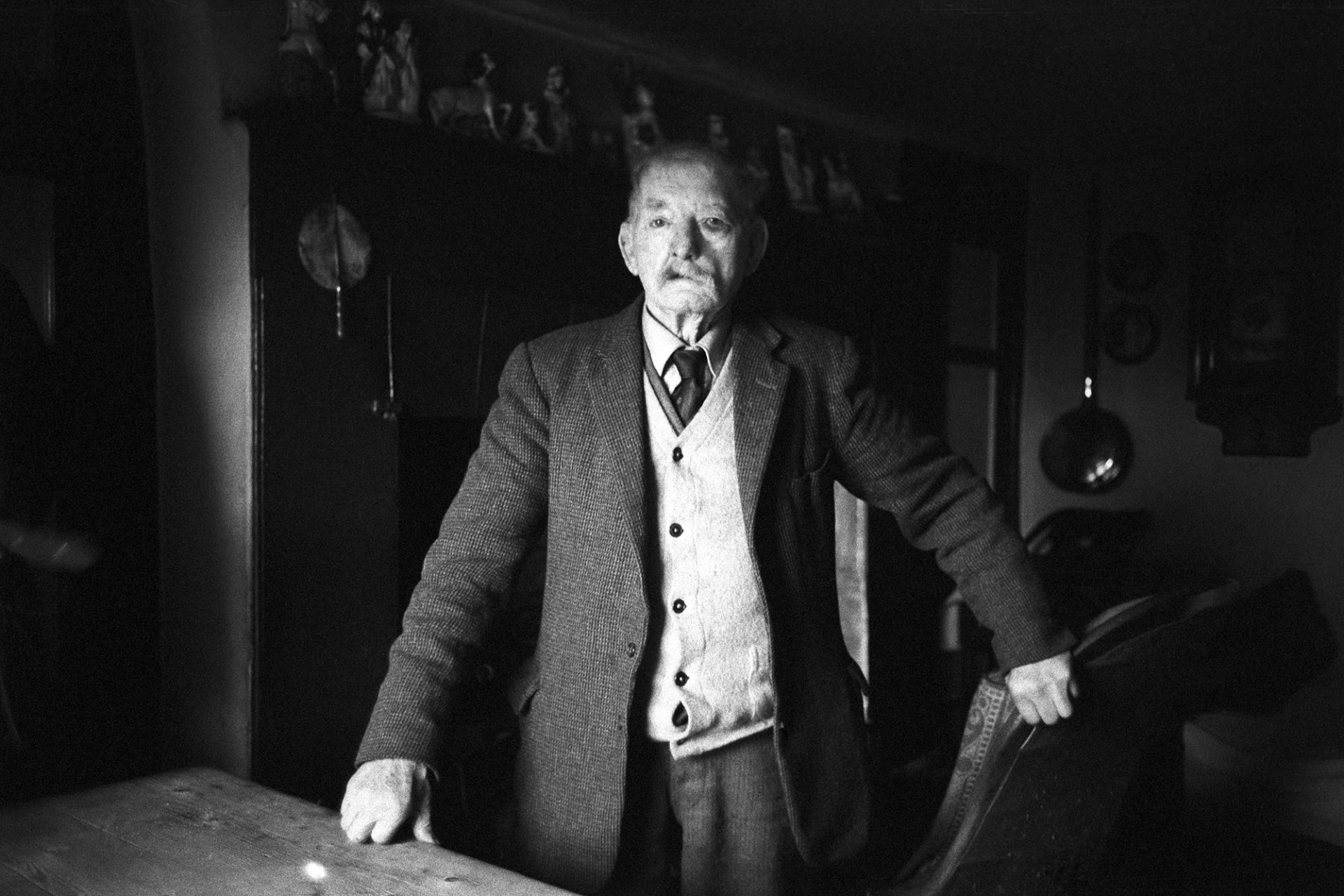 Portrait of old man, standing.<br />
[Reuben Clements standing by a table in Pear Tree Cottage, Dolton. He is in his nineties. He worked as a blacksmith and was also a bell ringer.]