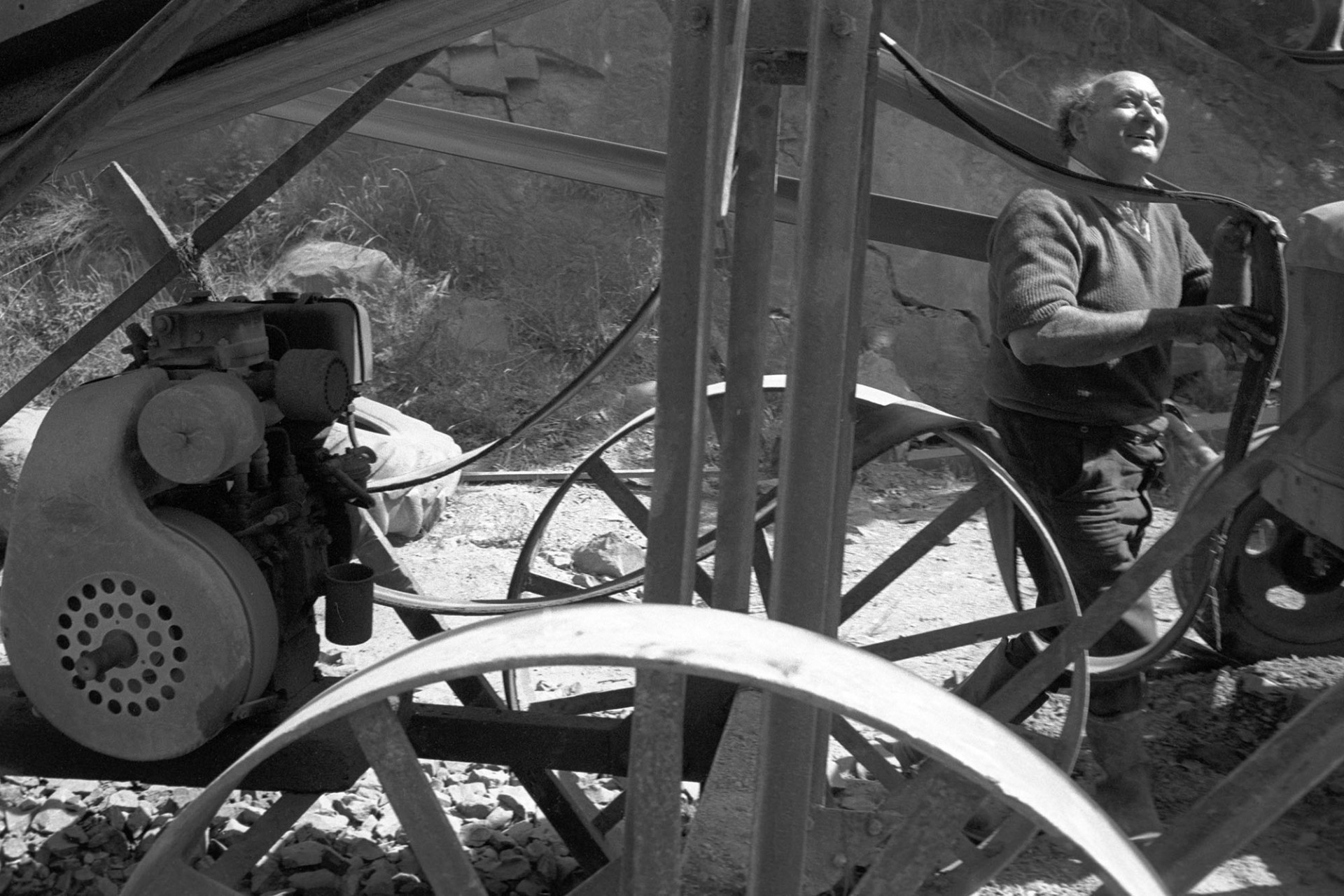 Man adjusting belt of stone crusher.
[Harold Glover working stone crushing machinery at New Bridge quarry, Dolton.]