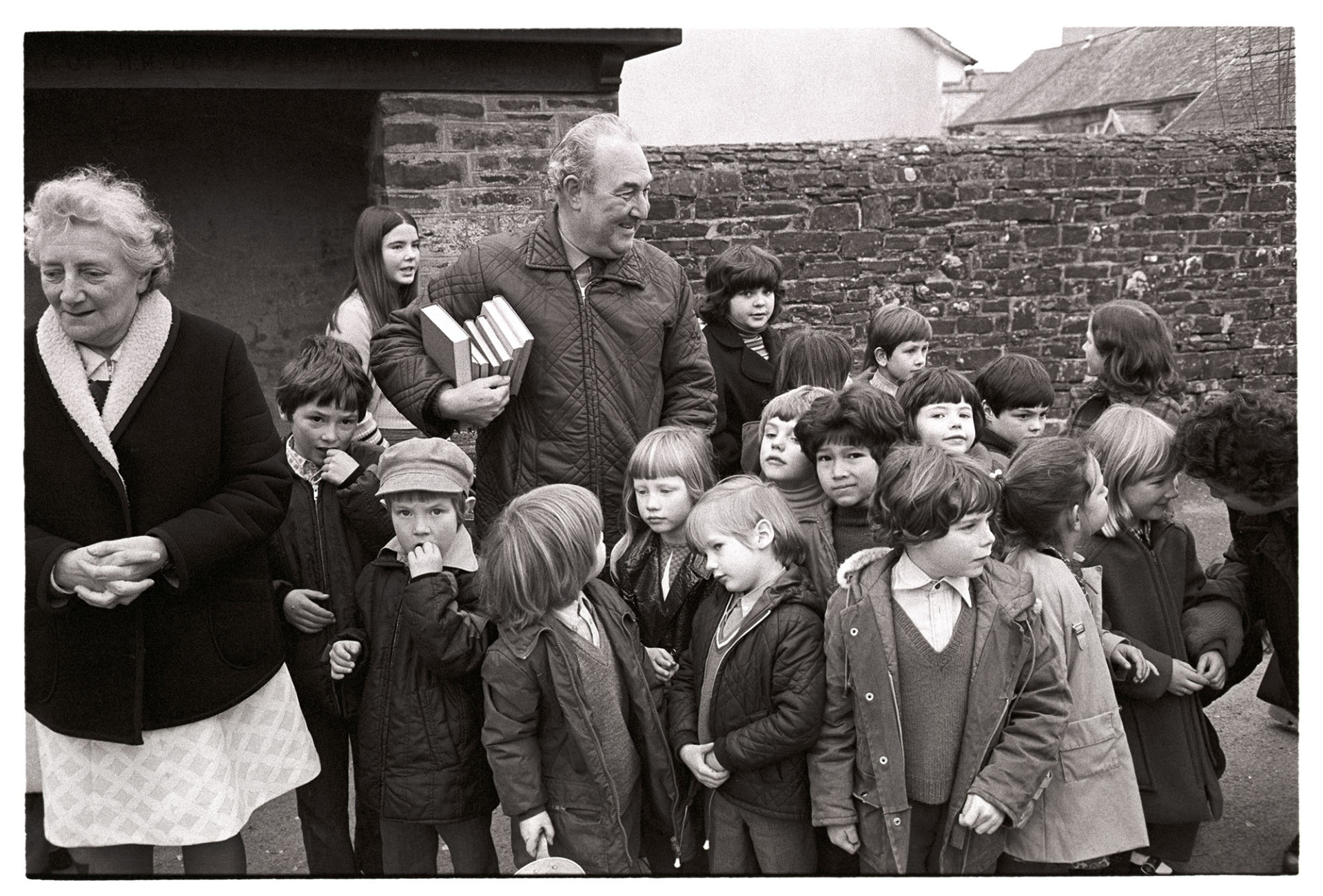 Schoolchildren with teachers after pancake race. 
[Two teachers with a group of schoolchildren at Dolton. The man is holding a pile of books.]