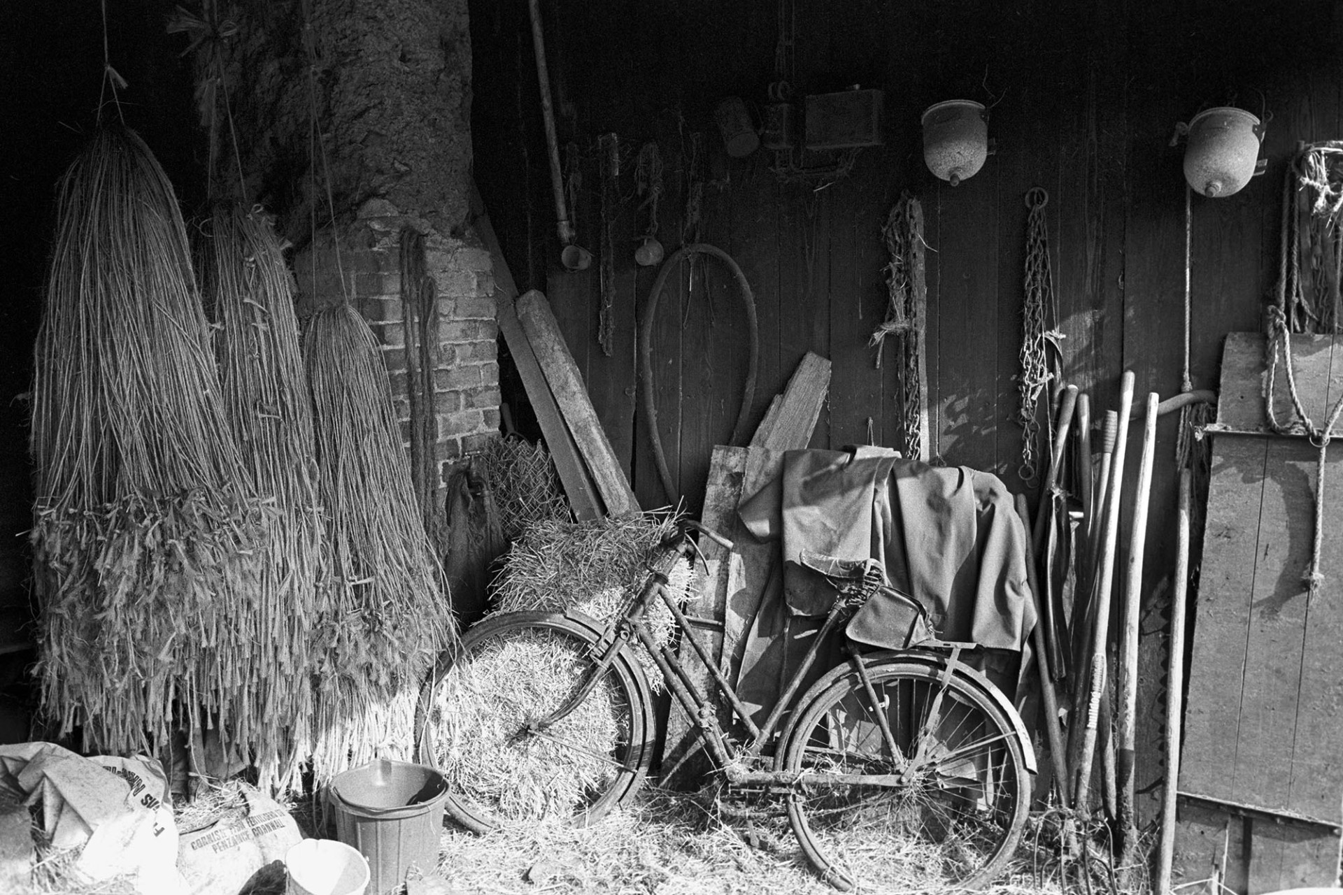 Tools, string, bicycle, etc. in corner of barn. 
[A barn with various items including rope, tools and a bicycle at Lower Bridge Farm, Lapford.]