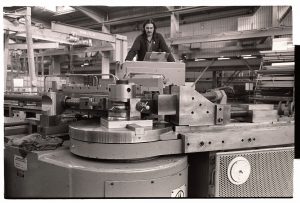Man operating bending machine in shipyard by James Ravilious