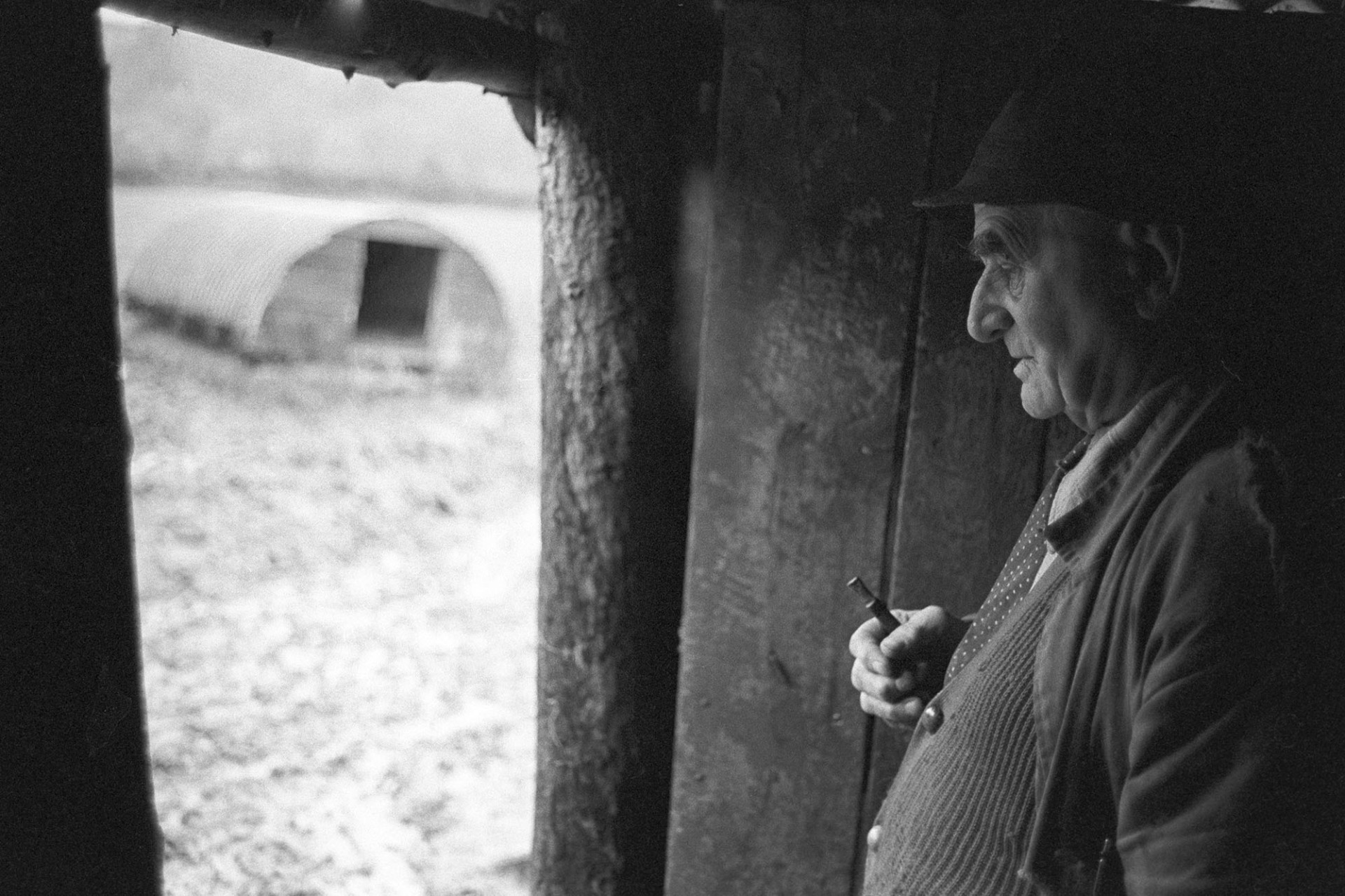 Man sheltering in shed.
[Archie Parkhouse sheltering in the doorway of a shed at Millhams in Dolton.]