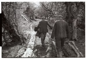 Cyril Bennett and George Bird walking down a muddy track by James Ravilious