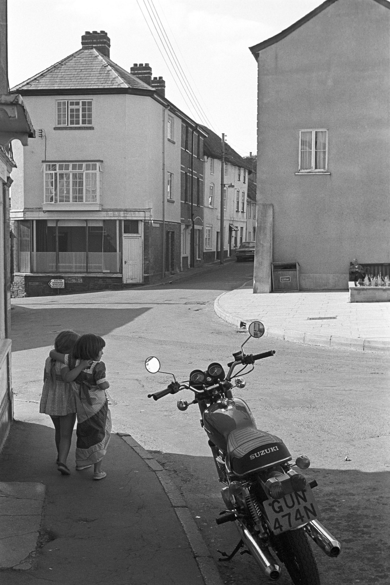 Street scene with children and Motorbike.
[Two children walking past a Suzuki motorbike in Fore Street, Chulmleigh.]