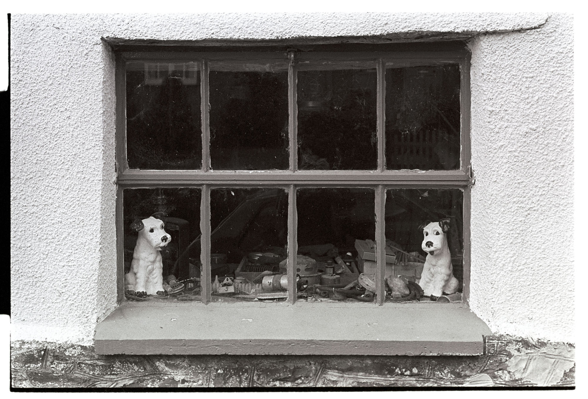 Window of workshop with two china dogs.
[Two china dogs looking out the window of a workshop, possibly in Bondleigh.]
