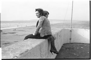 Couple sitting on sea wall by James Ravilious