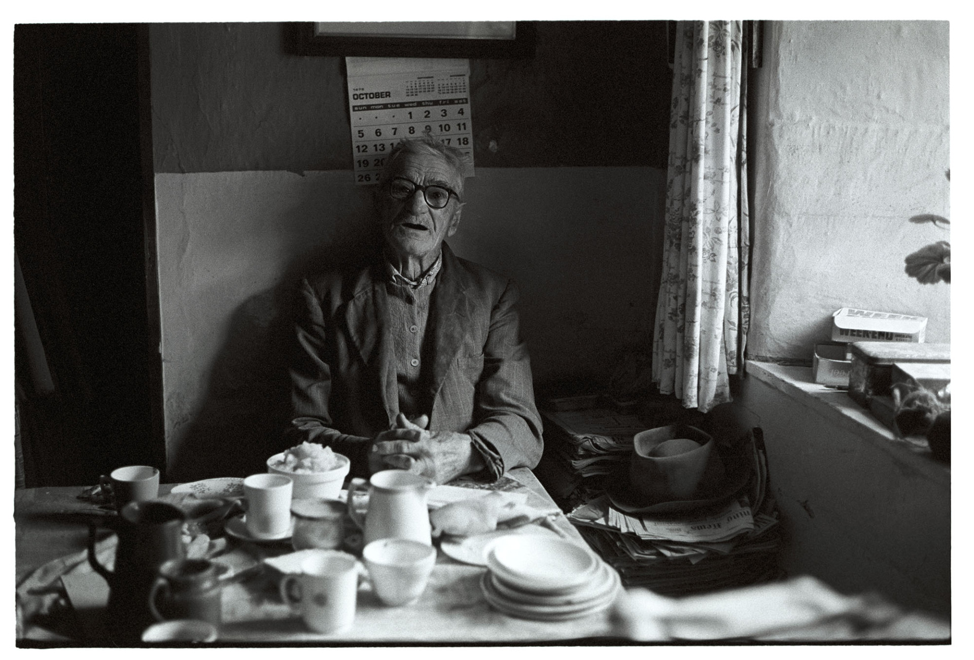 Elderly man seated at table.
[Percy Shaxton seated at a table by a window at No Place, Ebberley. Various items of crockery can be seen on the table.]