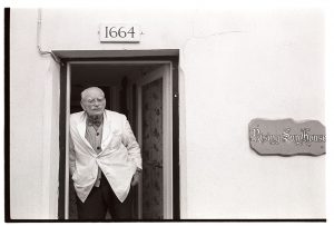 Man standing in doorway by James Ravilious
