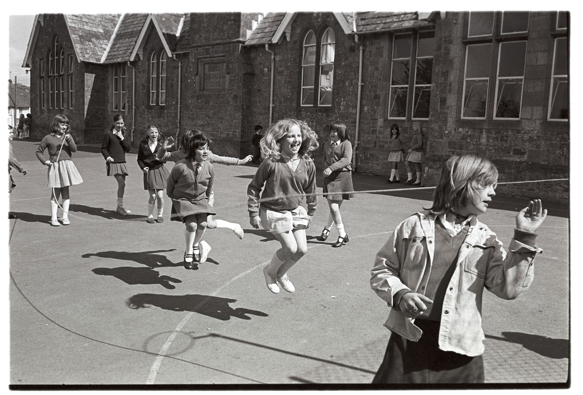 Schoolchildren skipping in the playground by James Ravilious
