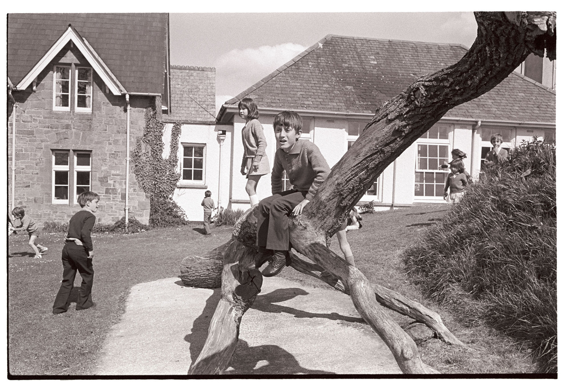 Schoolchildren in playground of school.
[Schoolchildren playing on a tree trunk in Hatherleigh School playground.]
