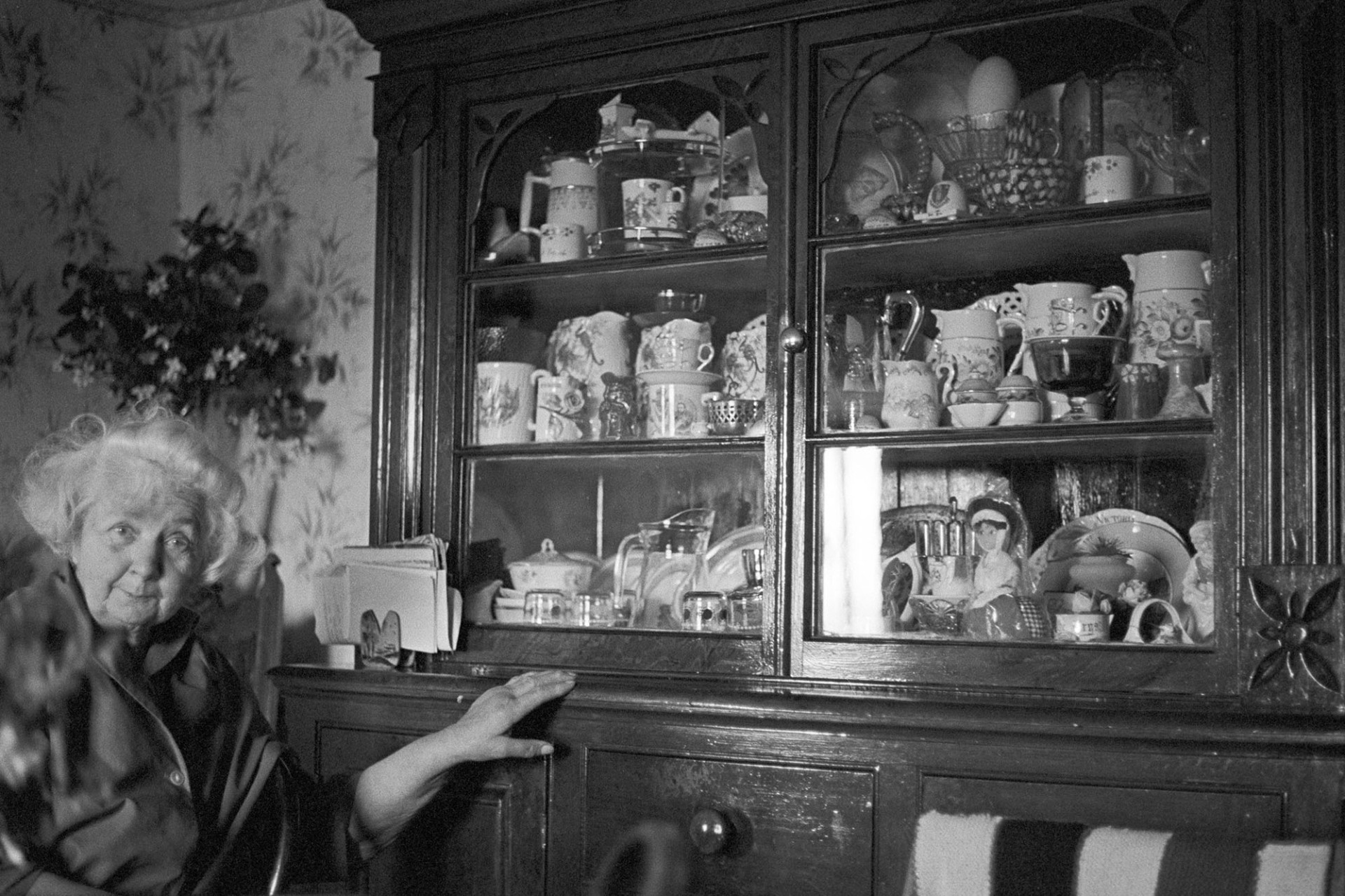 Old woman seated by dresser with china and ornaments.
[Gracie Fursedon at her home in Hatherleigh sat by her dresser with china and ornaments.]
