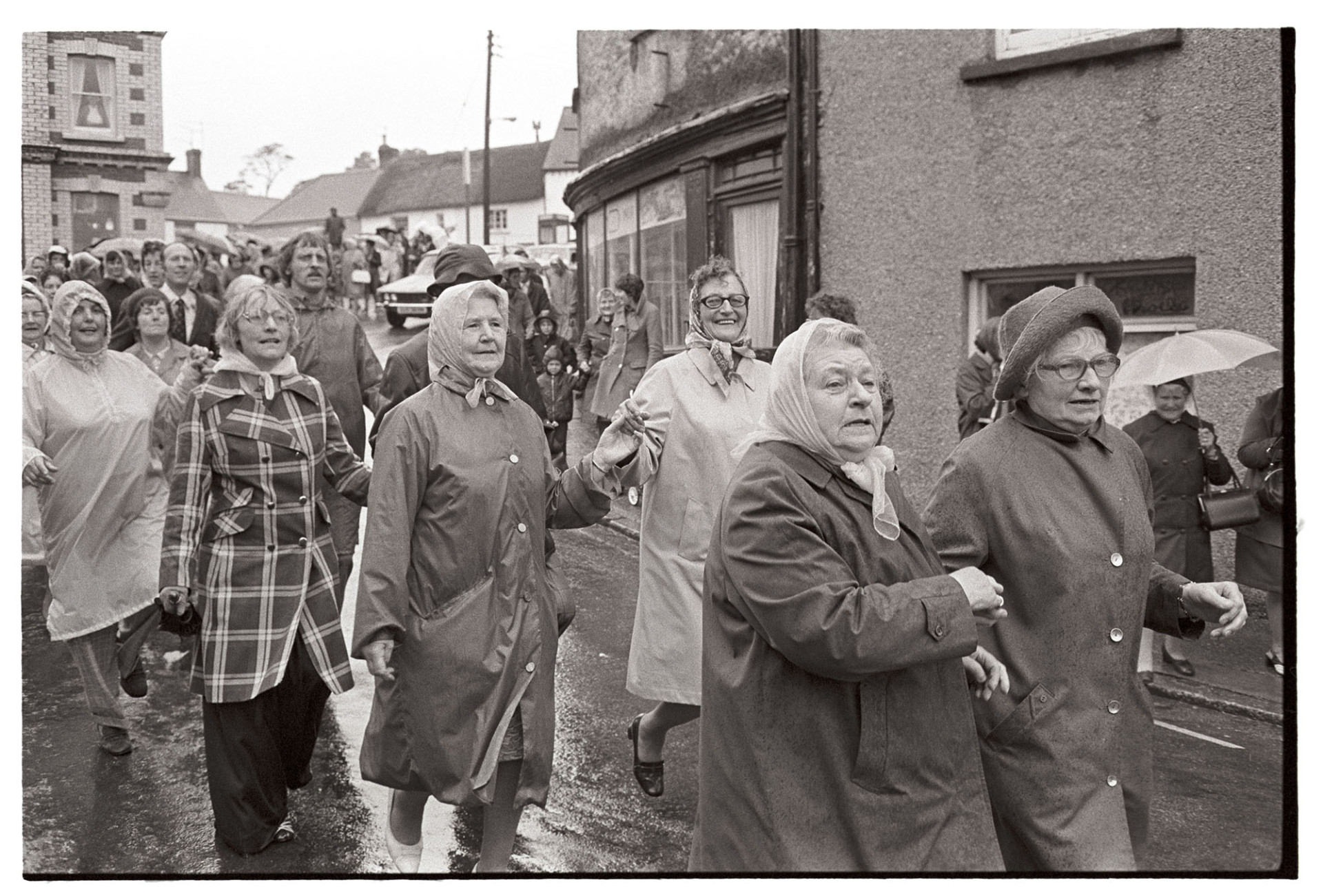 Women in Floral Dance through town in rain!
[A group of women wearing raincoats taking part in the Floral Dance through Hatherleigh, in the rain.]