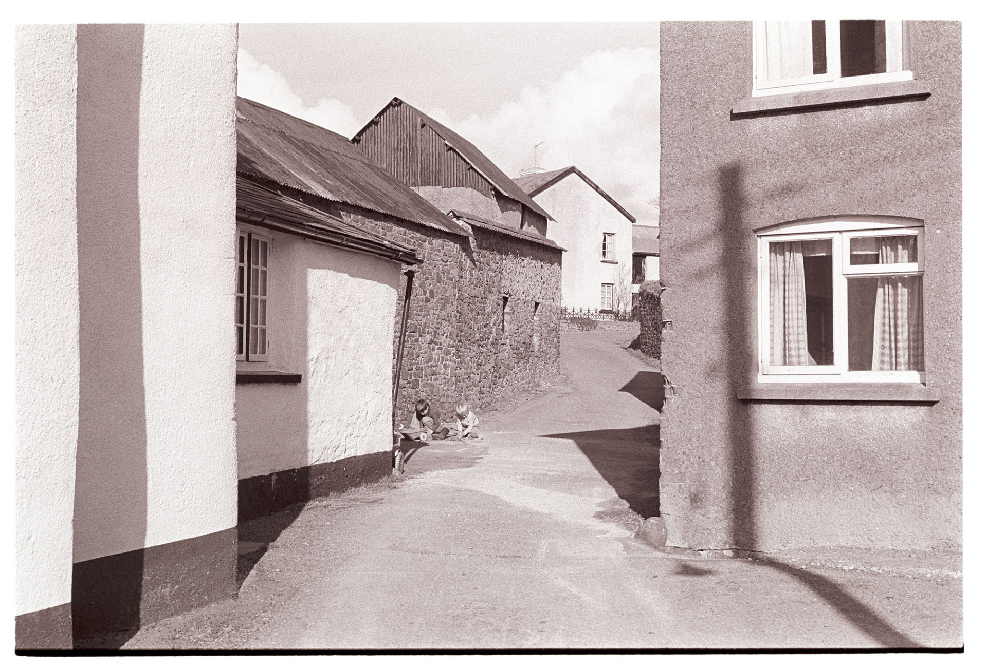 Village street, cob buildings.
[Two children playing in a street in High Bickington, in front of cob and stone buildings.]