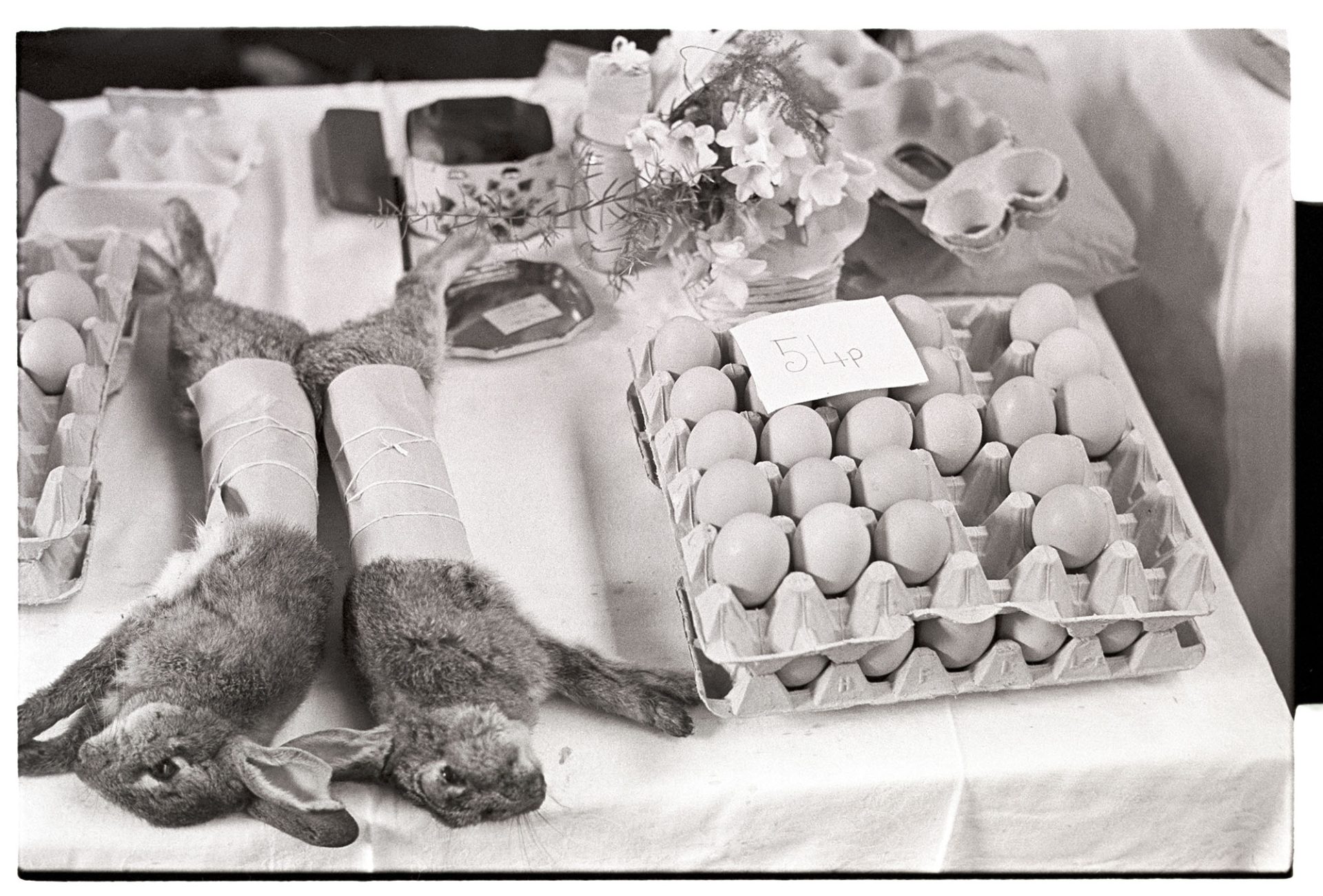 Eggs and rabbits on market stall.
[Eggs and rabbits for sale on a stall at Barnstaple Pannier Market.]